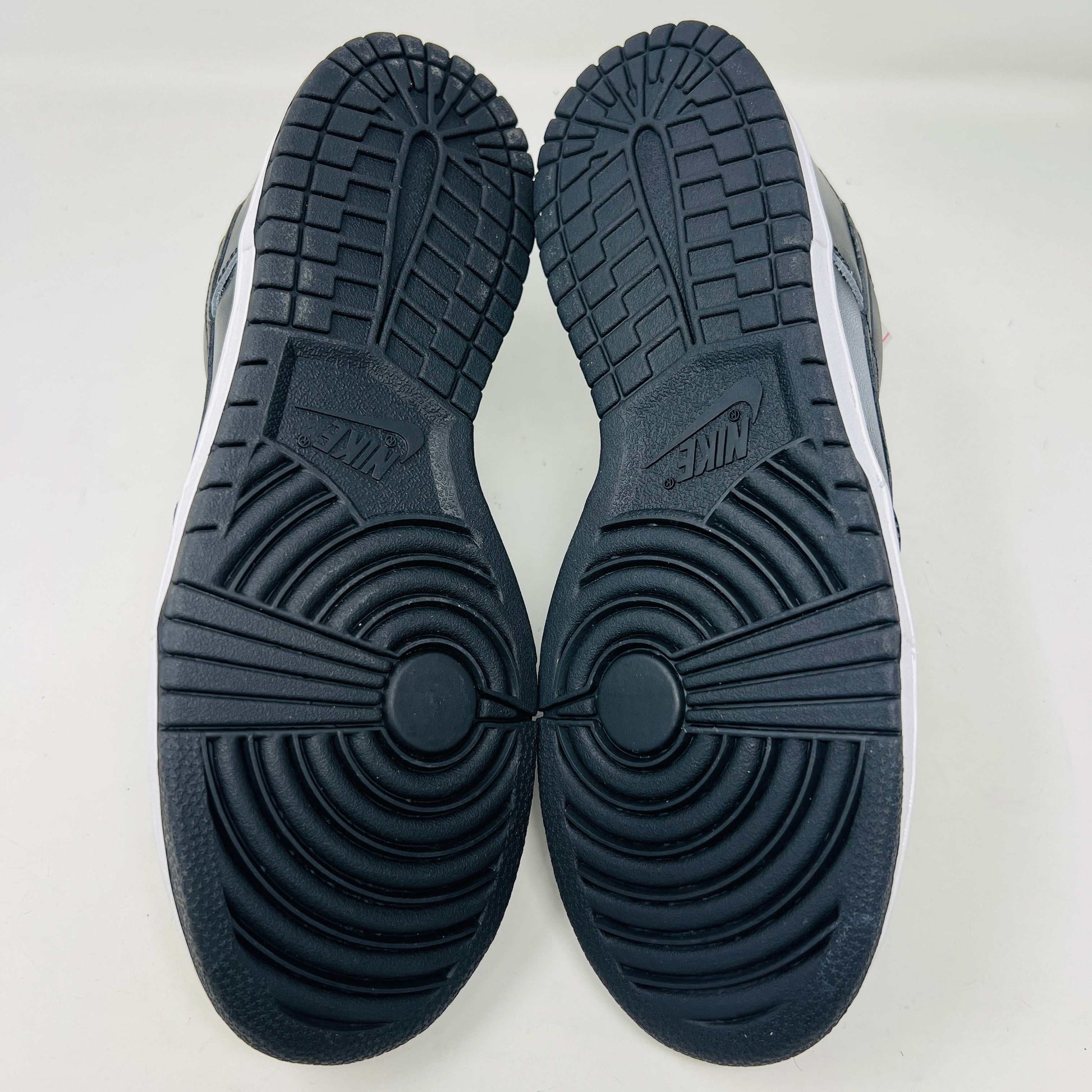 Authentic Nike Dunk Low Haze sneakers in black and white with white laces are displayed front-on against a white backdrop. A clear bag with extra black laces is on the left shoe.