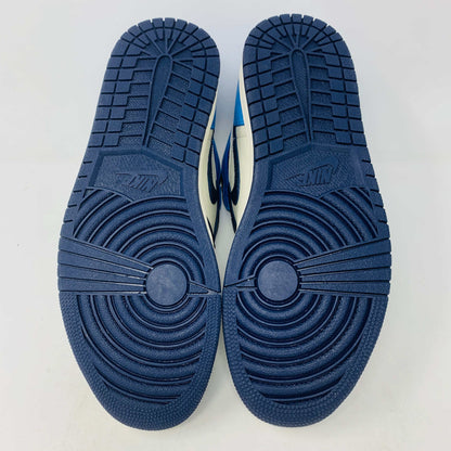 The new Jordan 1 Obsidian high-top sneaker, in blue and white with a black swoosh and blue laces, is displayed on a black and red box featuring 1985 Air Jordan 1 text. A printed Air Jordan wings logo is near the ankle.