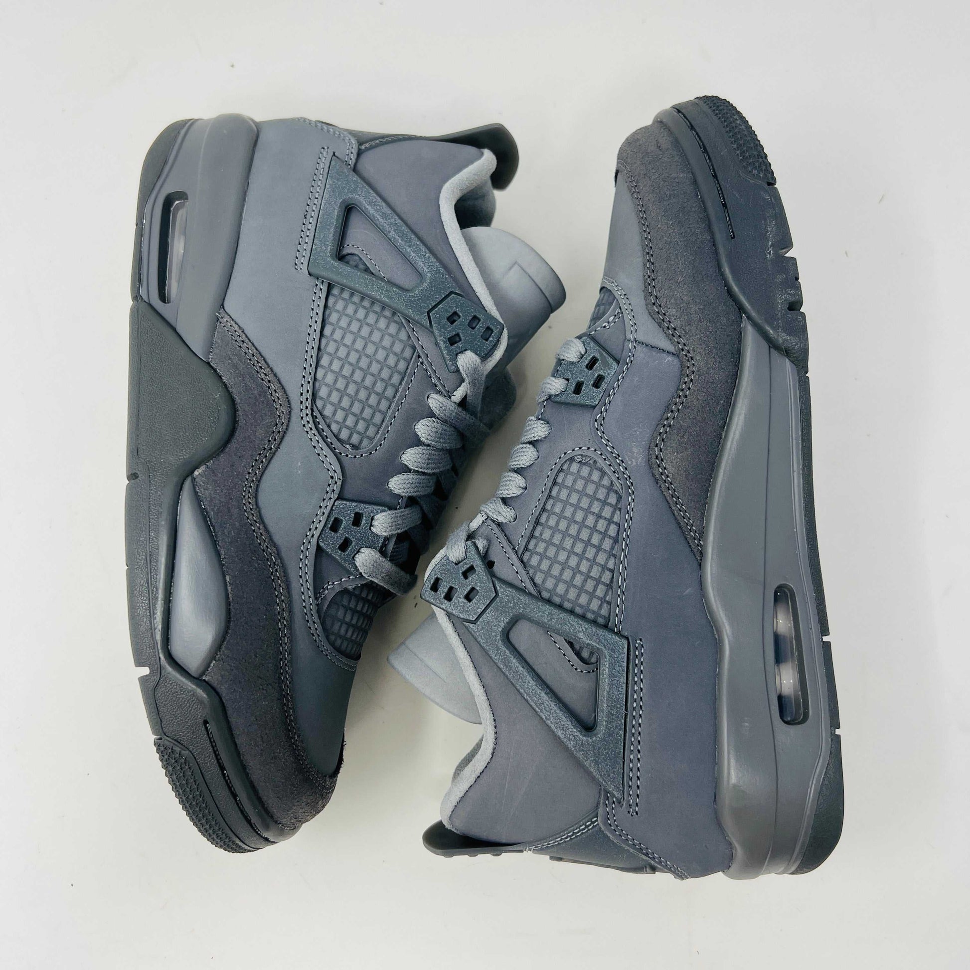 The Jordan 4 Retro SE Paris Olympics Wet Cement (GS), a brand-new gray sneaker, sits atop its pristine box. Featuring mesh and suede elements, it has a visible air unit in the midsole and a rubber outsole, poised to make an impression in 2024 against a plain white background.