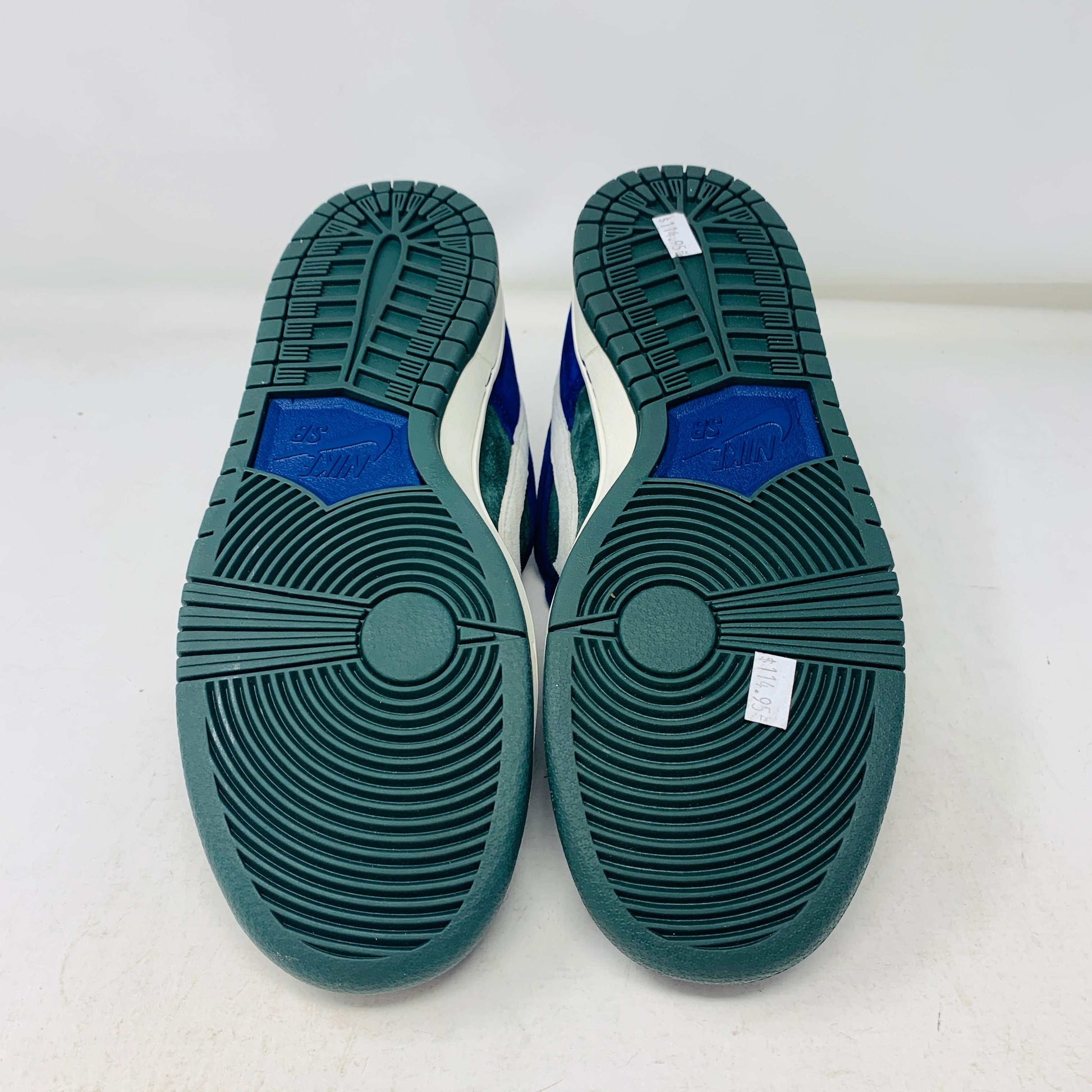 The Nike SB Dunk Low Deep Royal Blue sneaker, featuring a sleek blue and green design with a white swoosh, sits atop a purple Nike box. A bonus set of green laces accompanies the shoe, perfect for updating your style in 2024.