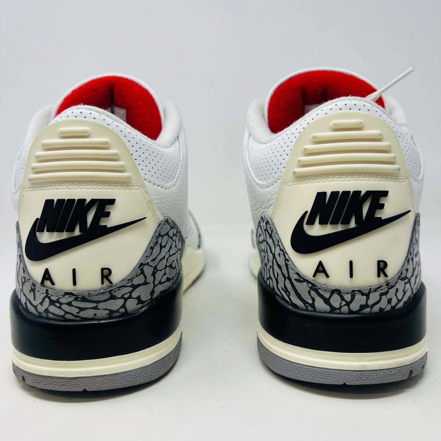 The Jordan 3 Retro White Cement Reimagined features white uppers with gray elephant print and red details, displayed on a black Nike Air shoebox. The size on the box reads 11, and the sneakers are pristine, free from heel drag.