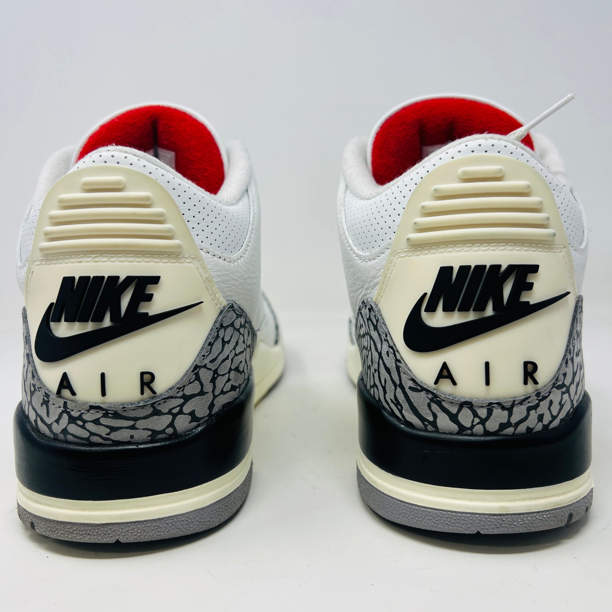 The Jordan 3 Retro White Cement Reimagined features white uppers with gray elephant print and red details, displayed on a black Nike Air shoebox. The size on the box reads 11, and the sneakers are pristine, free from heel drag.