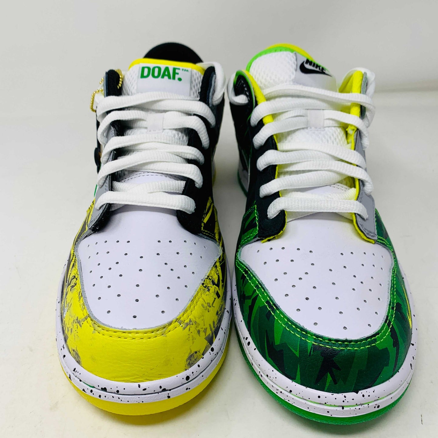 The Nike Dunk Low What the Duck Away University of Oregon PE is a vibrant sneaker featuring green, white, and black patterns with a black Nike swoosh outlined in yellow. It includes white laces, extra laces, a speckled white midsole, and a padded yellow lining atop a bright green shoebox. 100% authentic.