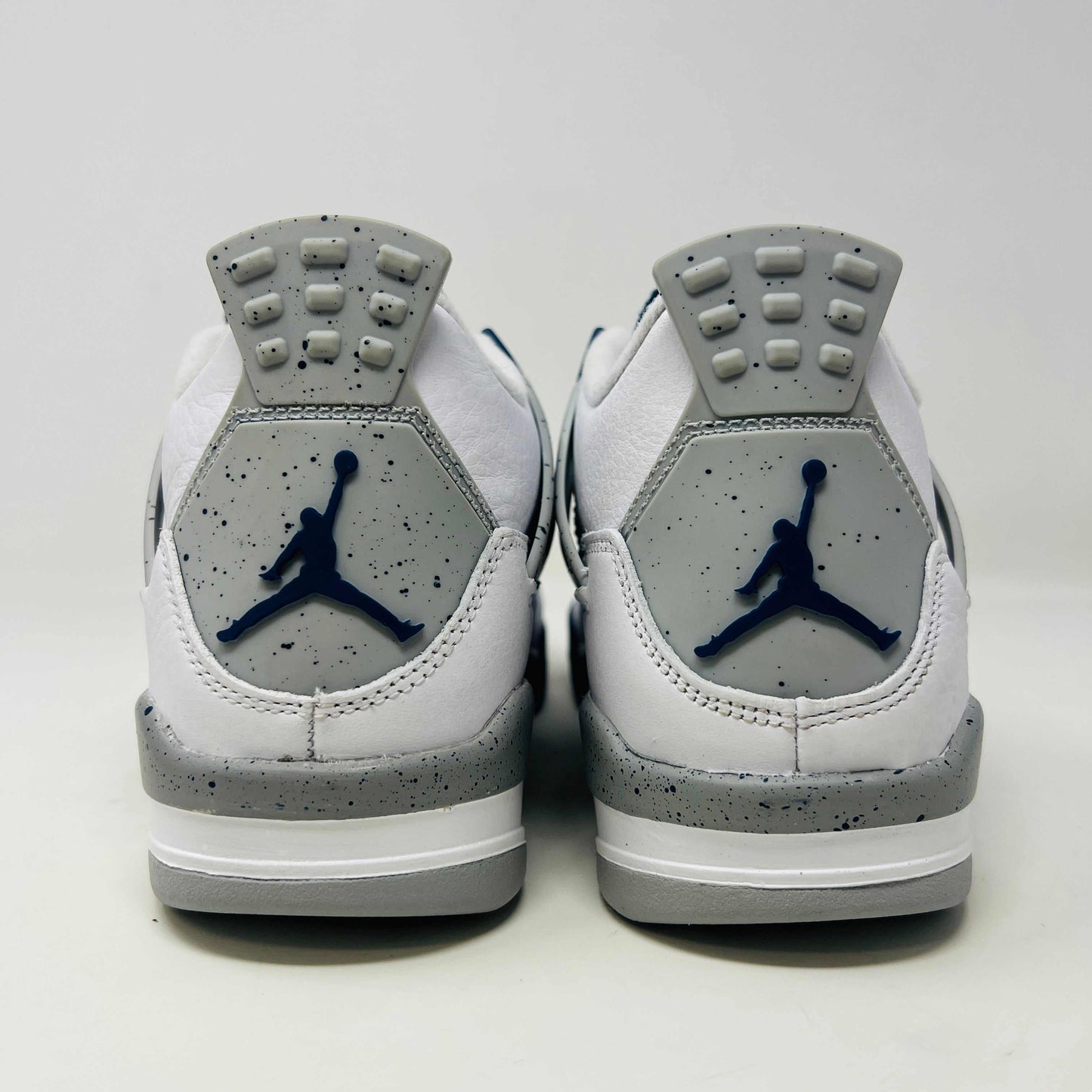 A brand new Jordan 4 Retro Midnight Navy (GS) sneaker from 2022 sits atop a red Nike shoe box with the iconic swoosh, featuring a white and gray design, leather and mesh mix, dark blue accents, and a visible air unit in the sole.