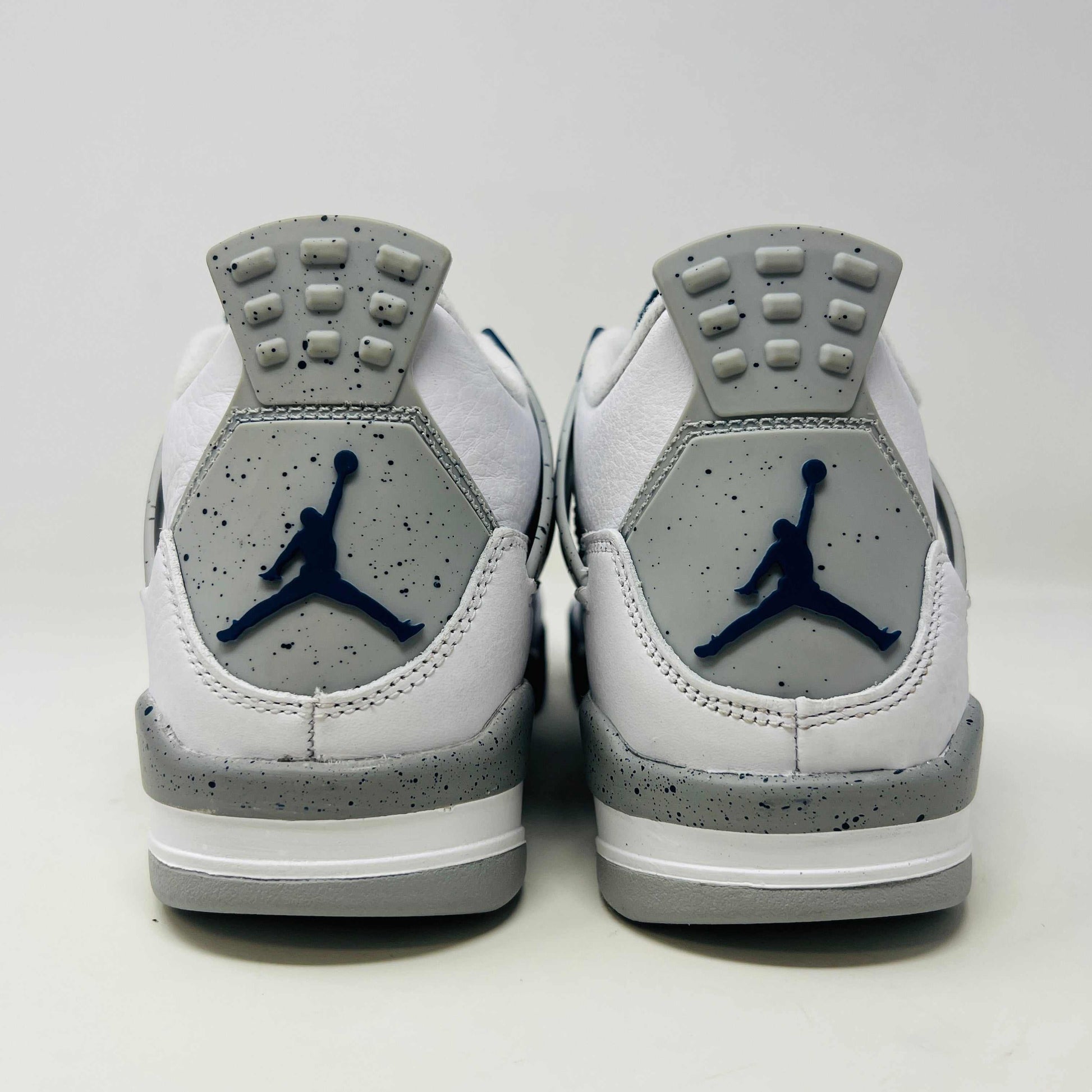A brand new Jordan 4 Retro Midnight Navy (GS) sneaker from 2022 sits atop a red Nike shoe box with the iconic swoosh, featuring a white and gray design, leather and mesh mix, dark blue accents, and a visible air unit in the sole.