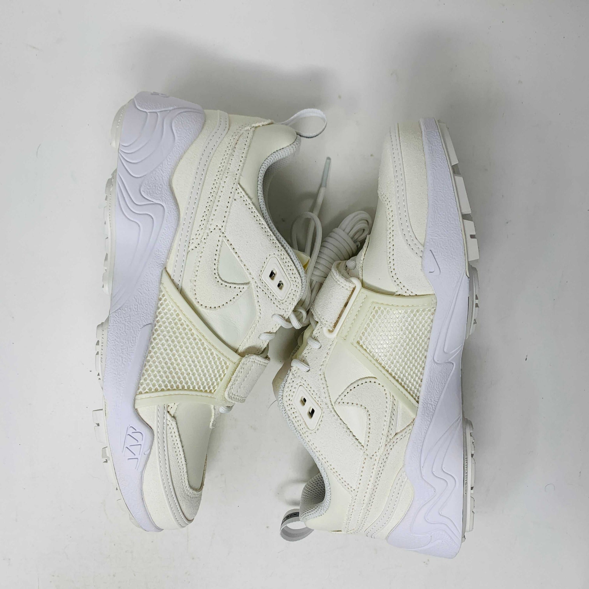 A pair of brand new, 100% authentic Nike Zoom Field Jaxx SP Travis Scott Sail sneakers feature a white colorway with a textured design and lace-up closure. The shoes, shown on a white background, have a thick sole and combine smooth and perforated panels.