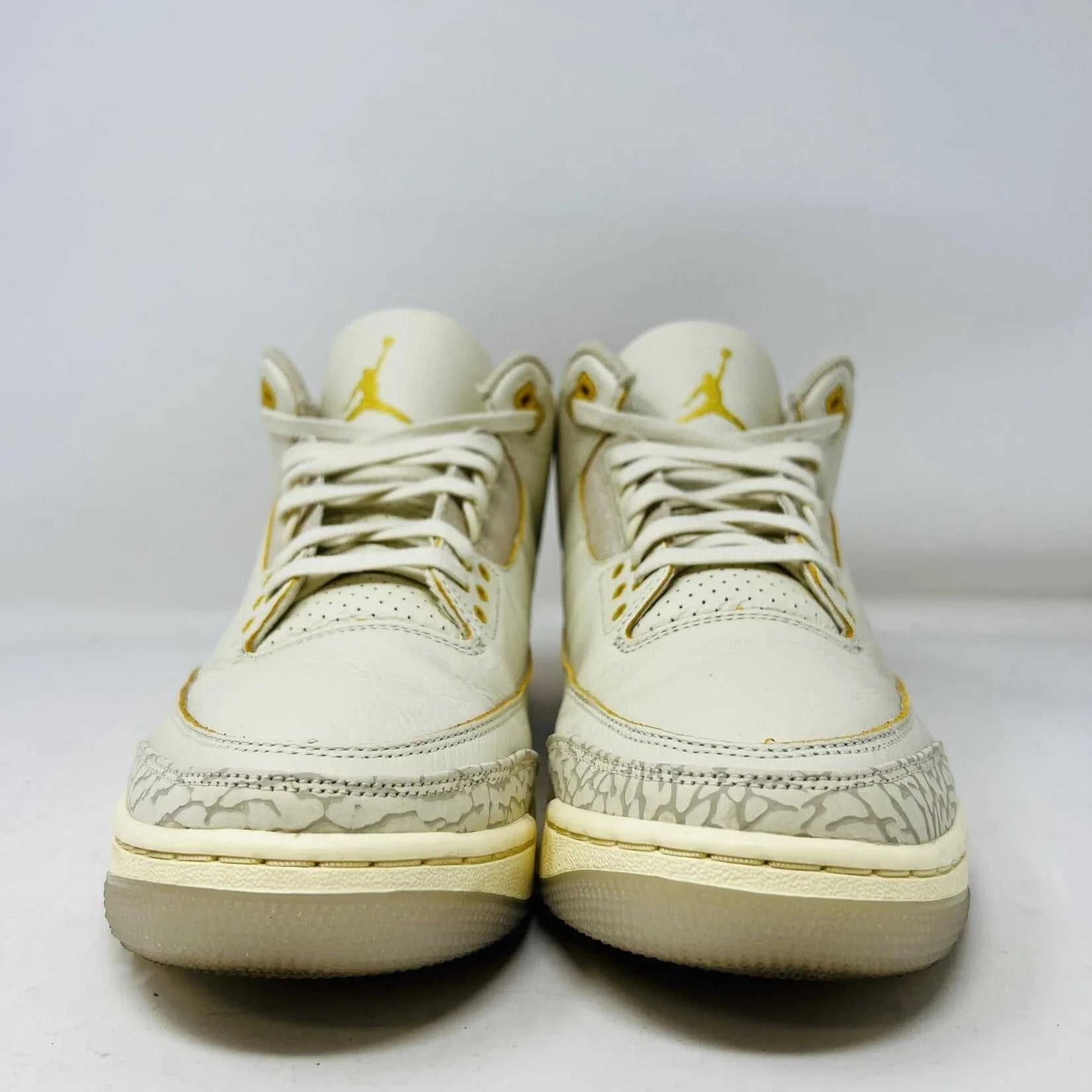 The Jordan 3 Retro SP J Balvin Medellín Sunset showcases clean cream uppers atop a shoebox with a gradient from yellow to dark red. A smiley face tag with lightning bolts confirms its 100% authenticity, highlighting this special 2023 release.