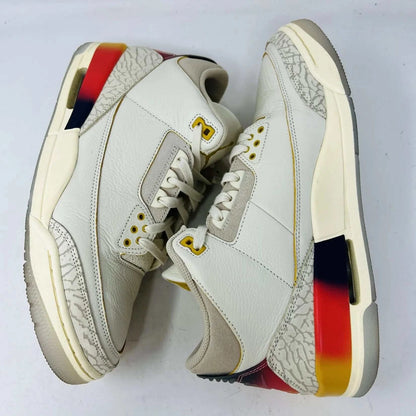 The Jordan 3 Retro SP J Balvin Medellín Sunset showcases clean cream uppers atop a shoebox with a gradient from yellow to dark red. A smiley face tag with lightning bolts confirms its 100% authenticity, highlighting this special 2023 release.