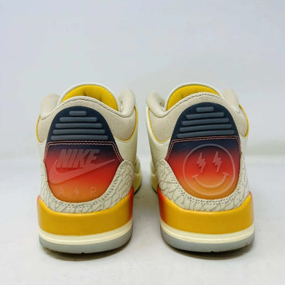 The Jordan 3 Retro SP J Balvin Medellín Sunset showcases clean cream uppers atop a shoebox with a gradient from yellow to dark red. A smiley face tag with lightning bolts confirms its 100% authenticity, highlighting this special 2023 release.