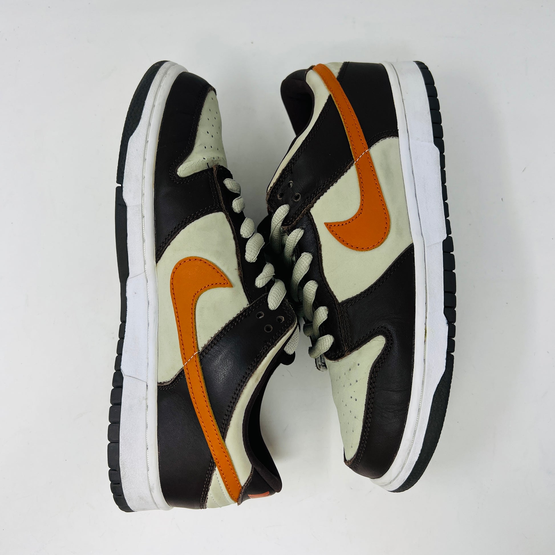 The Nike Dunk Low Pro B Light Stone Mesa Orange sneaker from 2002 is shown side-on, featuring sleek uppers in dark brown and cream with an orange swoosh. It rests elegantly on a white midsole with a black outsole against a plain background.