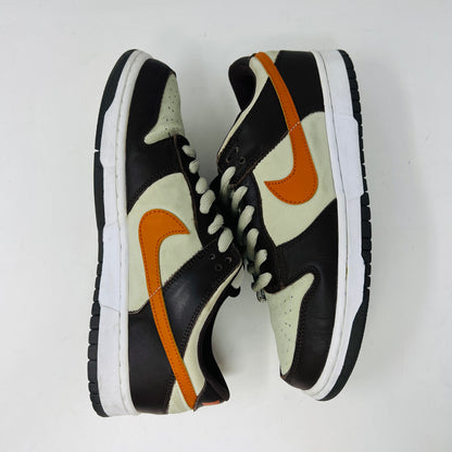 The Nike Dunk Low Pro B Light Stone Mesa Orange sneaker from 2002 is shown side-on, featuring sleek uppers in dark brown and cream with an orange swoosh. It rests elegantly on a white midsole with a black outsole against a plain background.