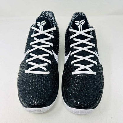 The KOBE Nike Kobe 6 Protro Mambacita Sweet 16 shoe, featuring clean black and white uppers, a white Swoosh, and a small gold 2 on the heel, is displayed on top of its black box with a Nike label. A sealed bag containing black laces accompanies the box for an authentic presentation.