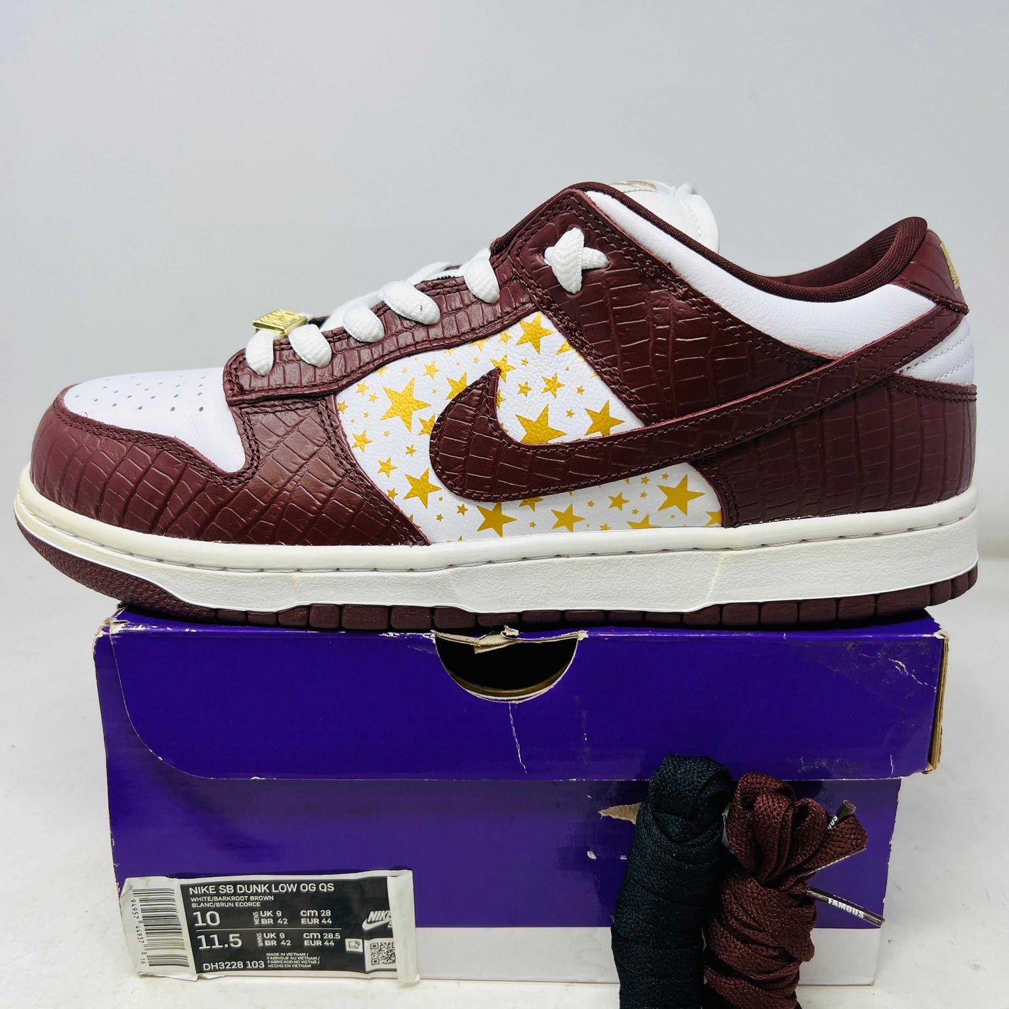 Nike SB Dunk Low Supreme Stars Barkroot Brown sneaker with yellow star accents on white side panel, textured brown leather uppers, white laces, and white midsole on purple box with extra laces and hang tag, 2021 model