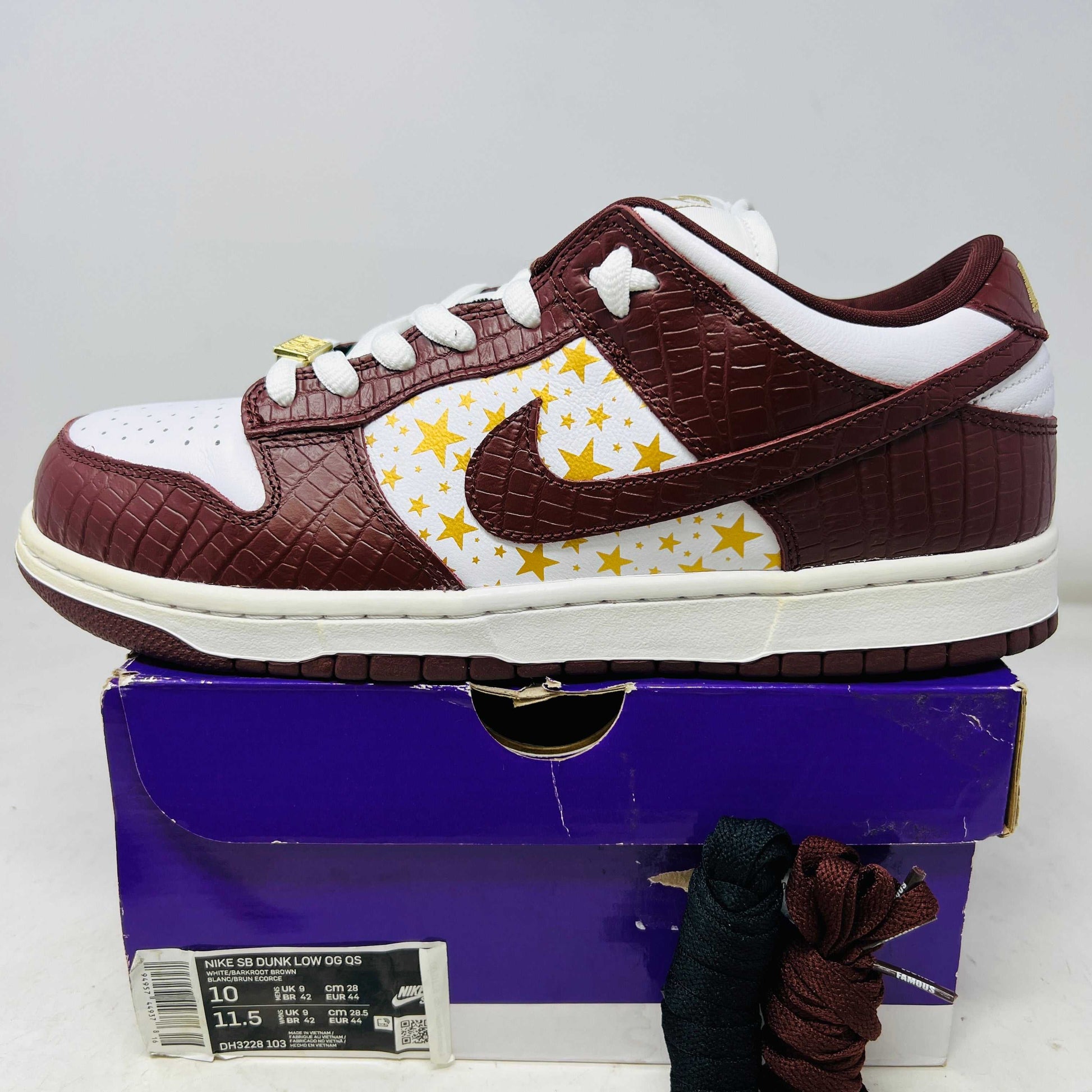 Nike SB Dunk Low Supreme Stars Barkroot Brown sneaker with yellow star accents on white side panel, textured brown leather uppers, white laces, and white midsole on purple box with extra laces and hang tag, 2021 model