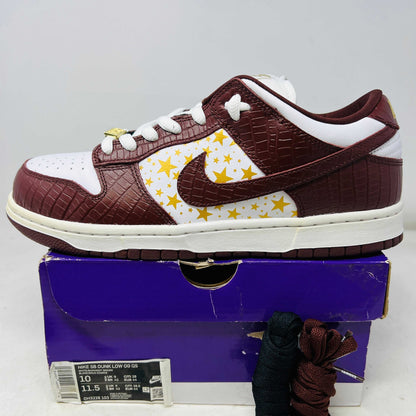 Nike SB Dunk Low Supreme Stars Barkroot Brown sneaker with yellow star accents on white side panel, textured brown leather uppers, white laces, and white midsole on purple box with extra laces and hang tag, 2021 model