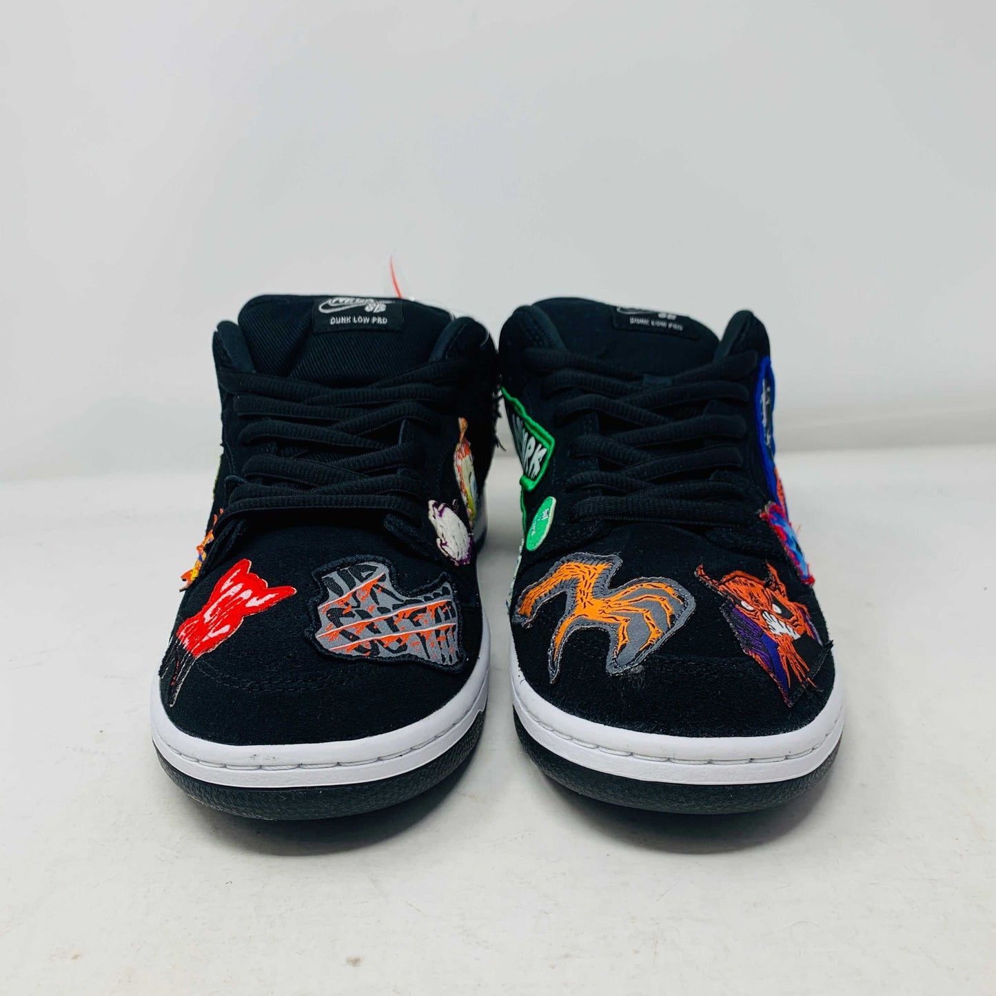 Authentic Nike SB Dunk Low Neckface sneakers, showcasing colorful animal and abstract patches, come in a vibrant green, yellow, and blue Nike SB box on a plain background. All sales final.