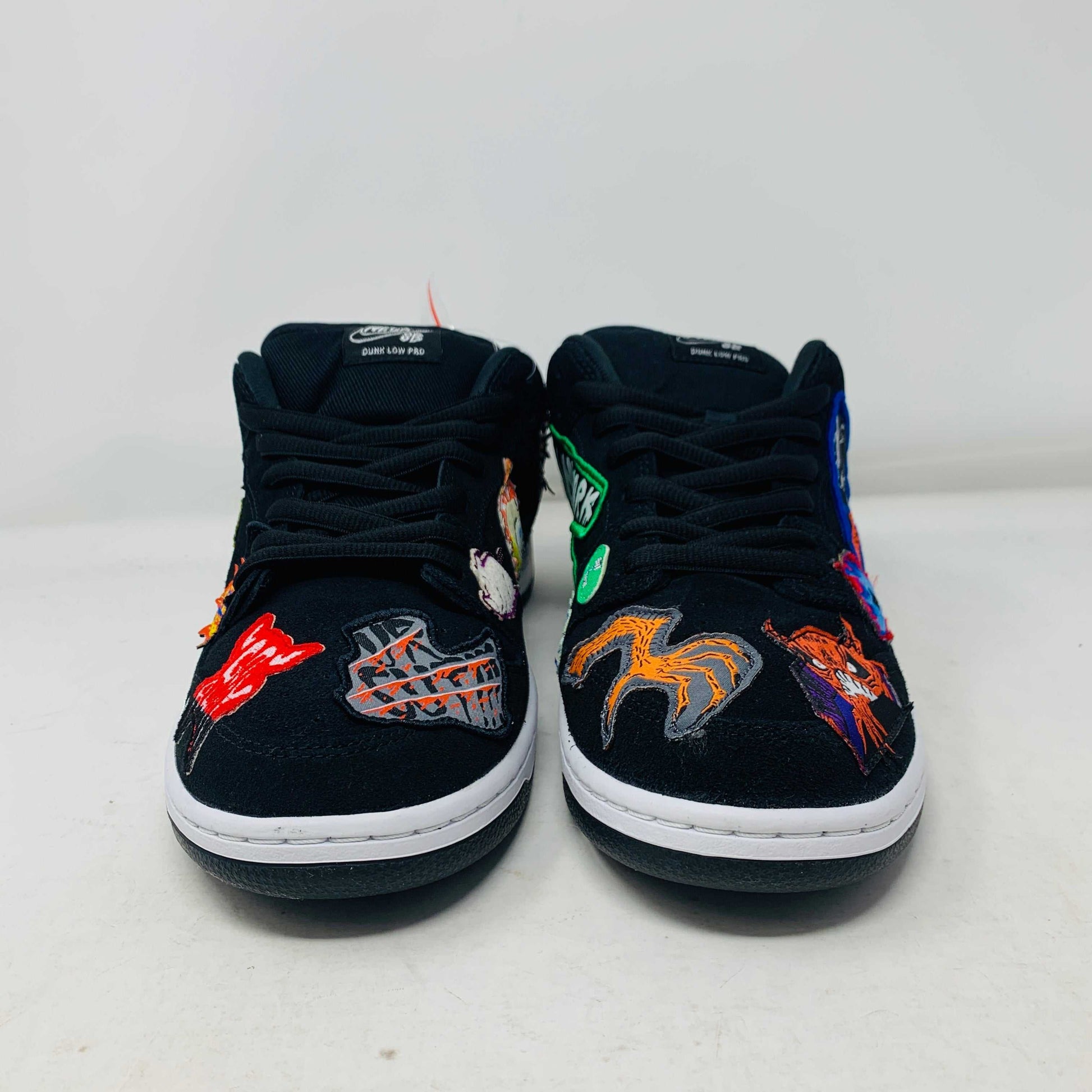 Authentic Nike SB Dunk Low Neckface sneakers, showcasing colorful animal and abstract patches, come in a vibrant green, yellow, and blue Nike SB box on a plain background. All sales final.