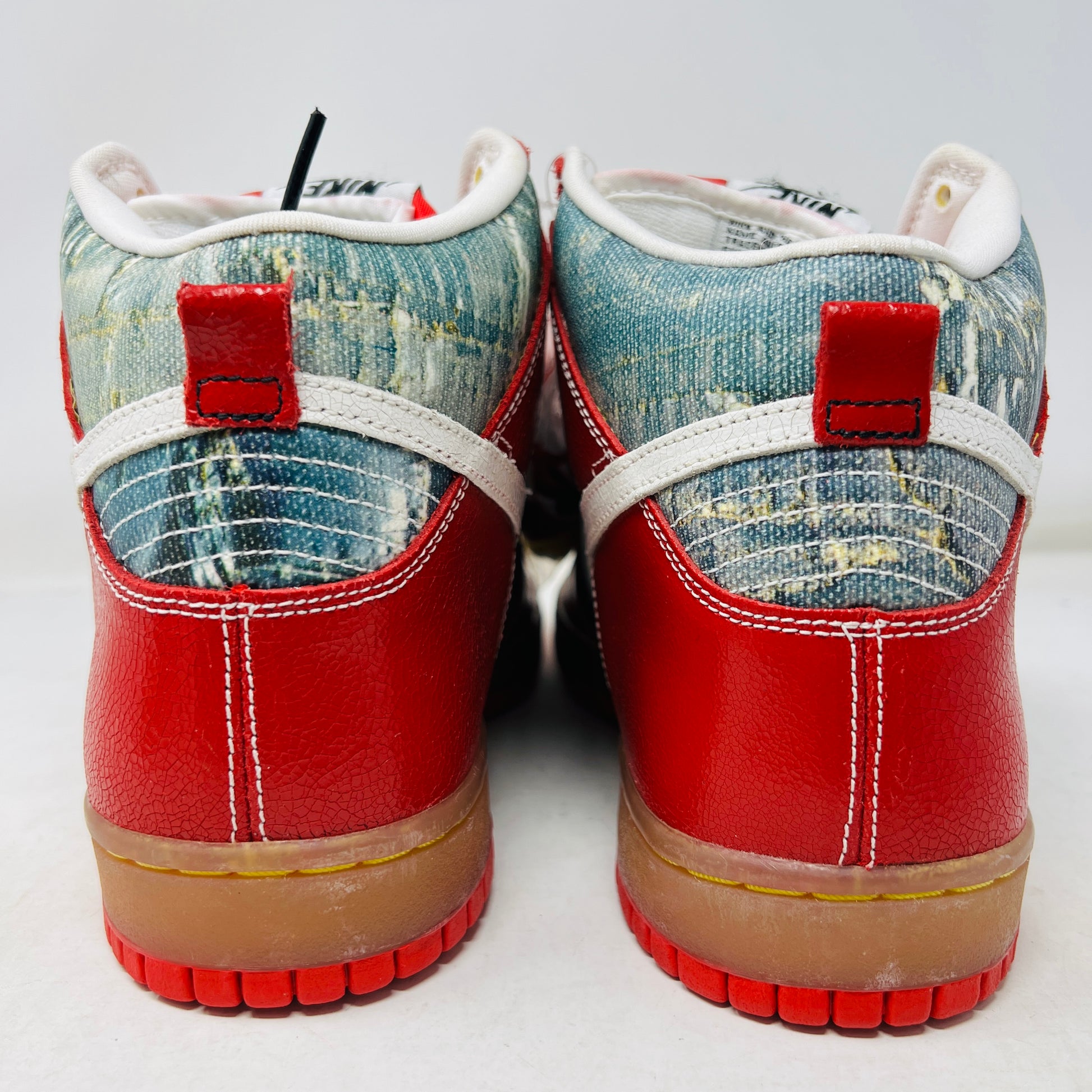 The Nike SB Dunk High Shoe Goo from 2008, priced at $525, sits atop its box. It features red and blue denim sections, a white swoosh, and a gum sole. A tag shows size and numbers, with extra laces beside the shoebox.
