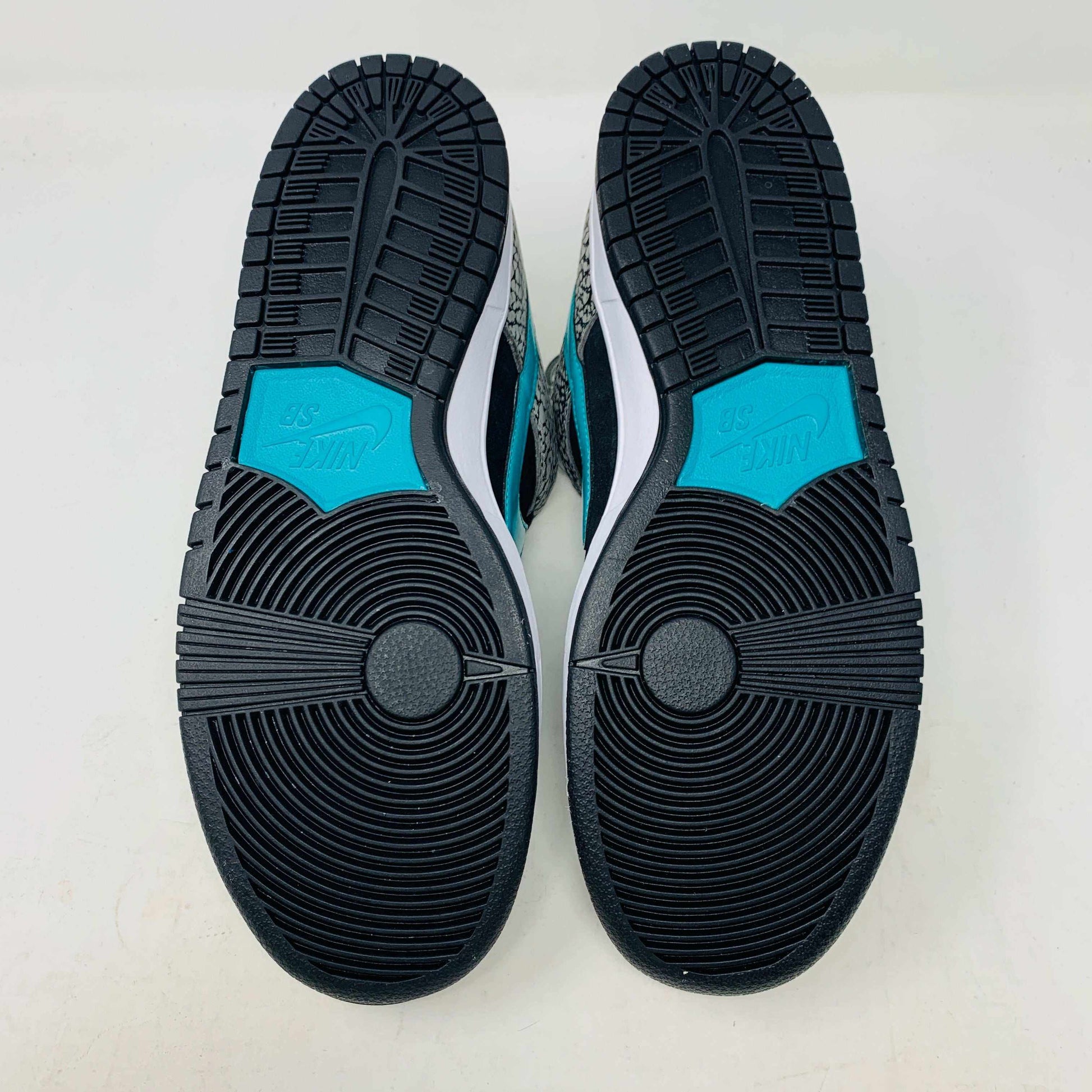 The Nike SB Dunk Low atmos Elephant sneakers feature a black and white textured pattern, teal Nike swoosh, and black laces, displayed on a purple Nike SB box with a white swoosh logo, ensuring 100% authenticity.