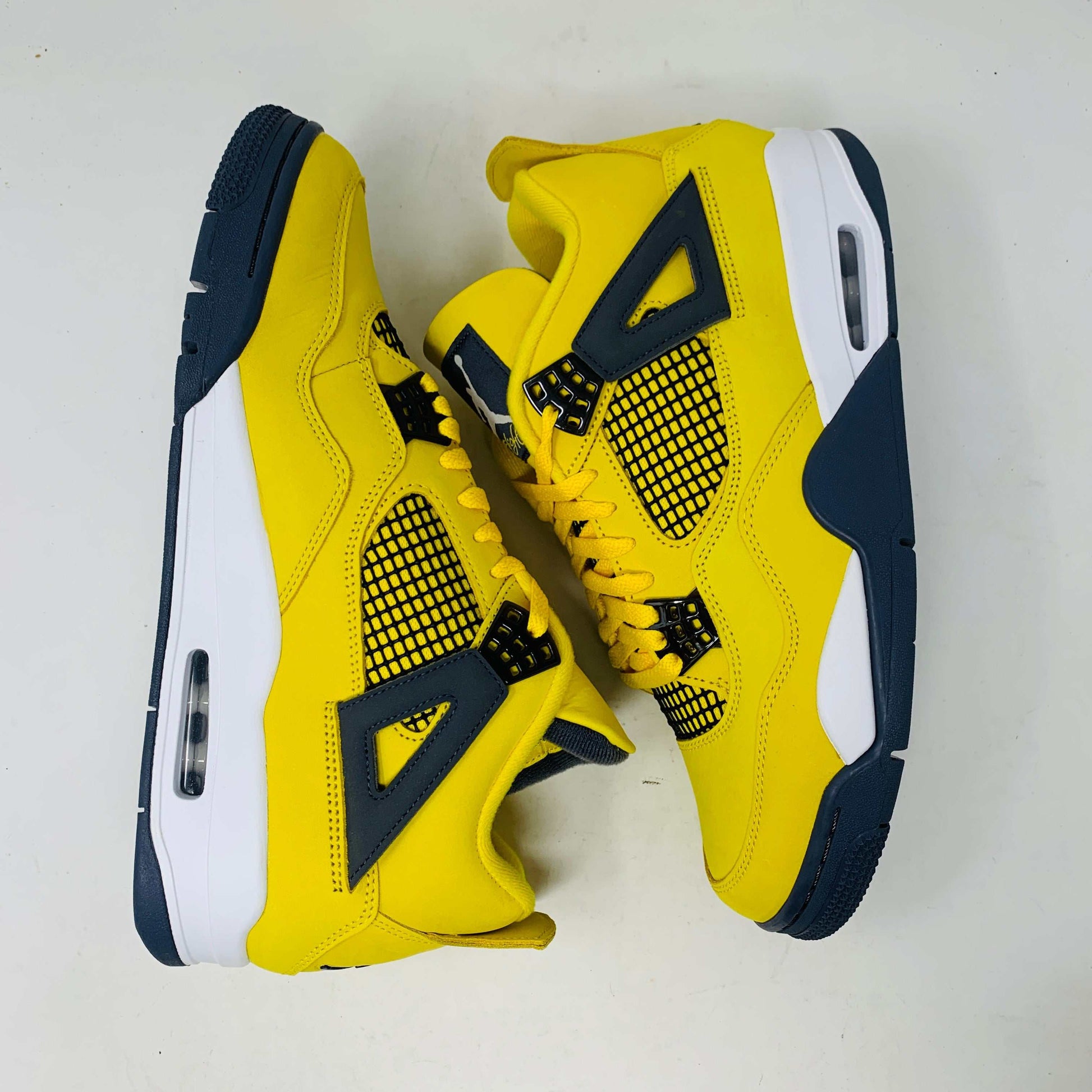 Jordan 4 Lightning sneakers in bold yellow and black with premium materials and lightning bolt accents.