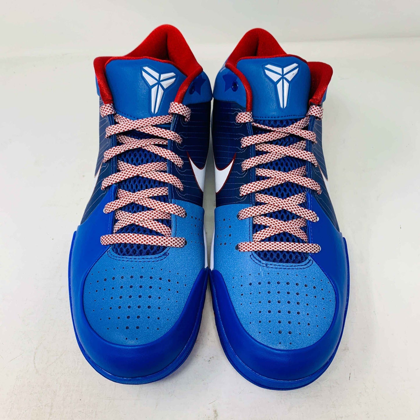 The Nike Kobe 4 Protro Philly (2024) basketball shoes are blue with red interiors and laces, featuring a white Nike logo on the tongue. They include perforated detailing on the toe area and a white swoosh on the sides, all set against a white background.