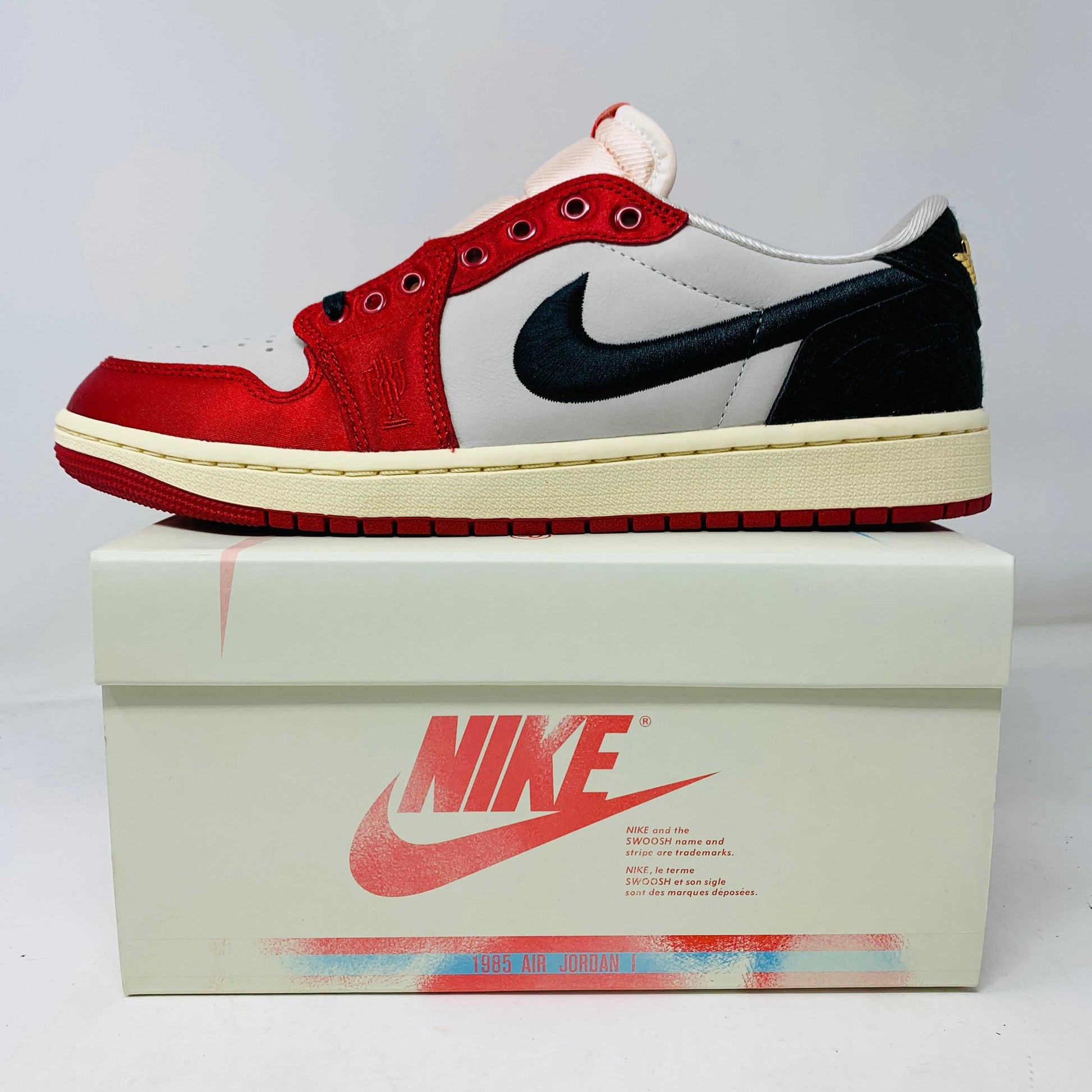 Jordan 1 Retro Low OG Trophy Room Away sneakers with red, black, and white design, new condition, includes white and yellow laces, 2024 model.