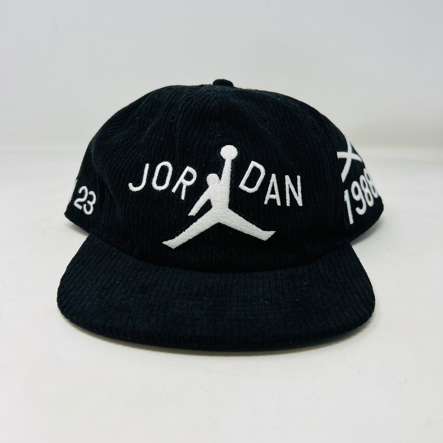 The Jordan x Nina Chanel Abney Club Cap Black features a sleek design with a stylized basketball player logo and JORDAN in white, the number 23 on the left, and 1988 on the right. It boasts a classic flat brim style.