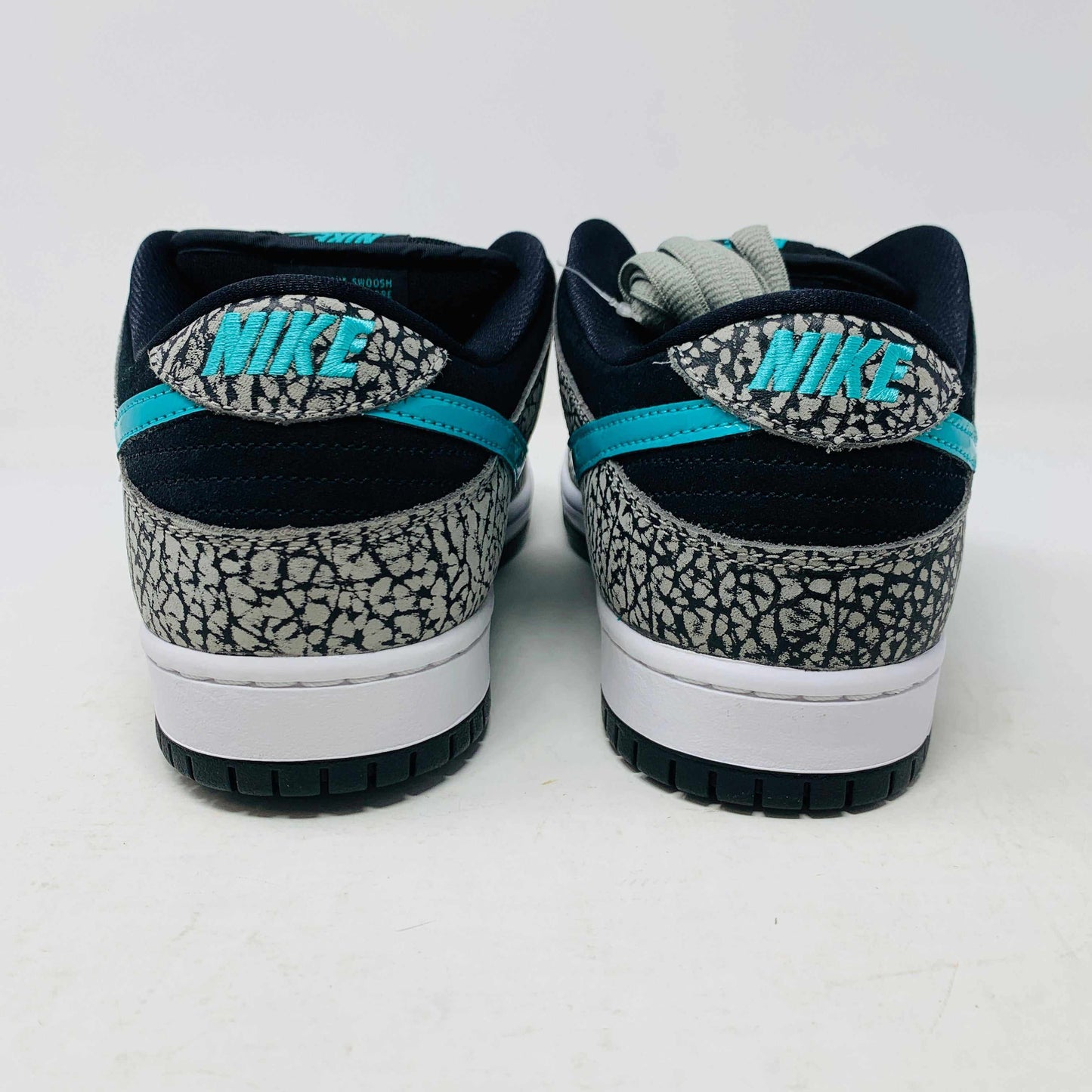 The Nike SB Dunk Low atmos Elephant sneakers feature a black and white textured pattern, teal Nike swoosh, and black laces, displayed on a purple Nike SB box with a white swoosh logo, ensuring 100% authenticity.