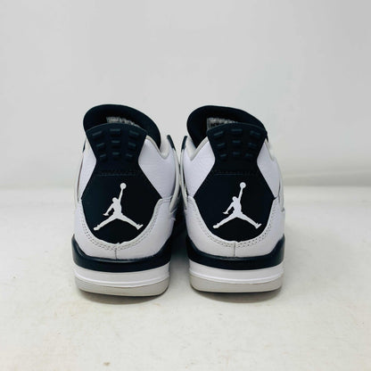 The Jordan 4 Military Black GS sneakers, featuring distinctive side netting and a logo on the tongue, are brand new and authentic in white and gray with black accents. They face forward on a white surface against a plain background, embodying modern style.