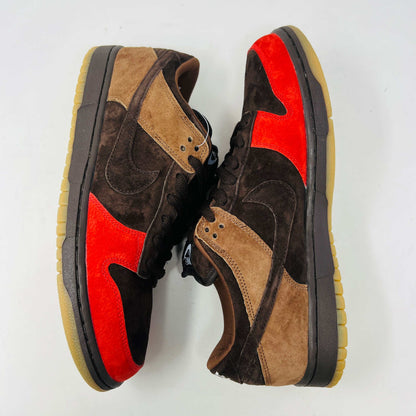 A pair of BRAND NEW Nike SB Dunk Low Bison sneakers featuring brown and red suede uppers, black laces, EXTRA LACES included, and a light brown sole. Positioned side by side on a white background, they promise to be 100% authentic and stylish.