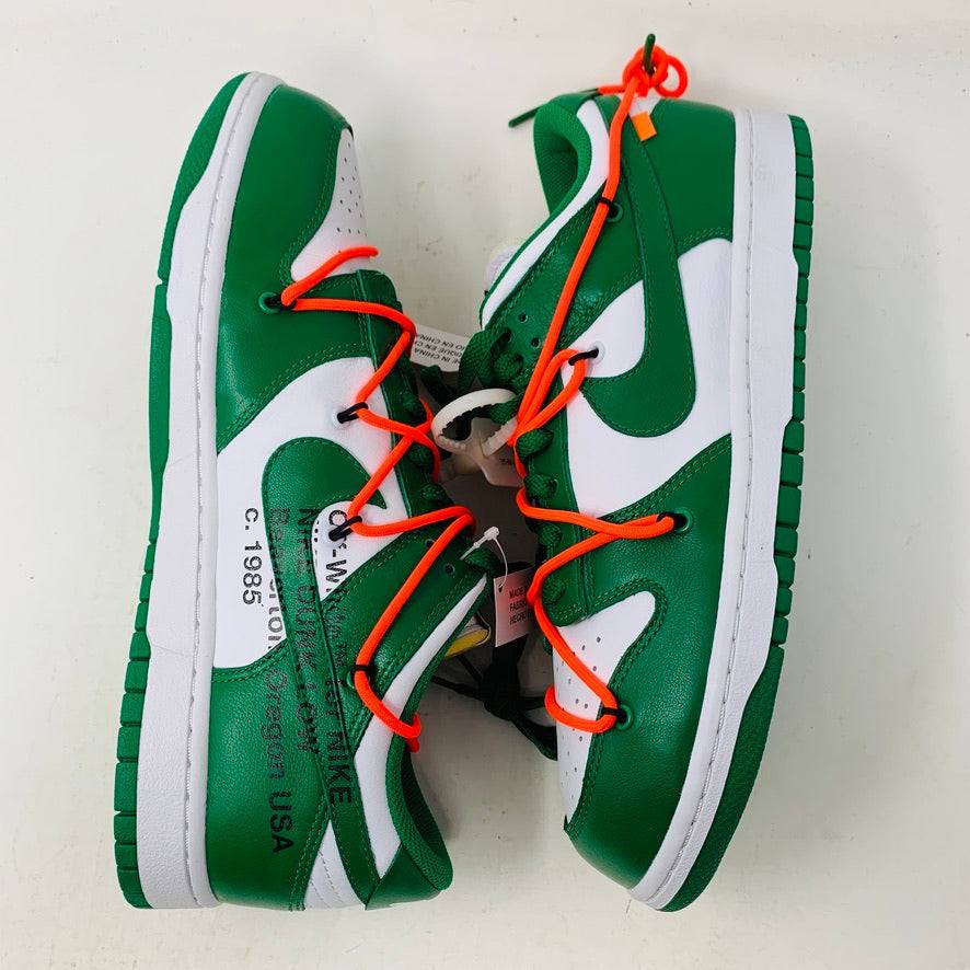 The Nike Dunk Low Off White Pine Green sneaker, accented with bright orange laces, rests on a shiny silver box. This authentic 2019 release by Nike boasts a sleek white tag, highlighting its new allure.