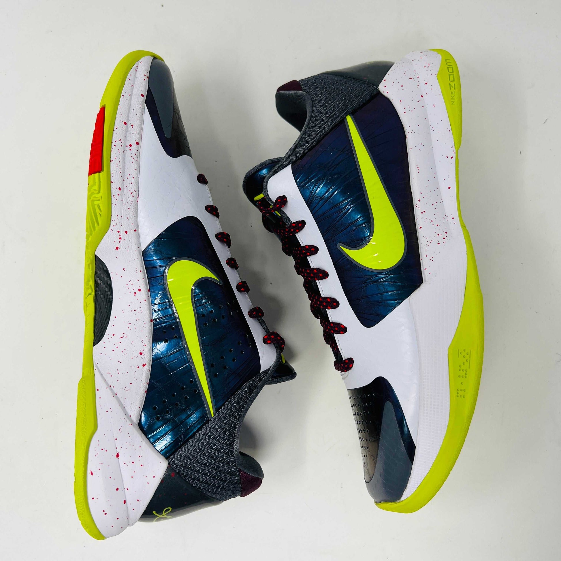 The Nike Kobe 5 Protro Chaos sneaker, authentic and vibrant, is showcased on a black shoe box. It features a bright lime green Nike swoosh, purple and white accents, a speckled pink midsole, red-speckled laces, and a textured gray heel.