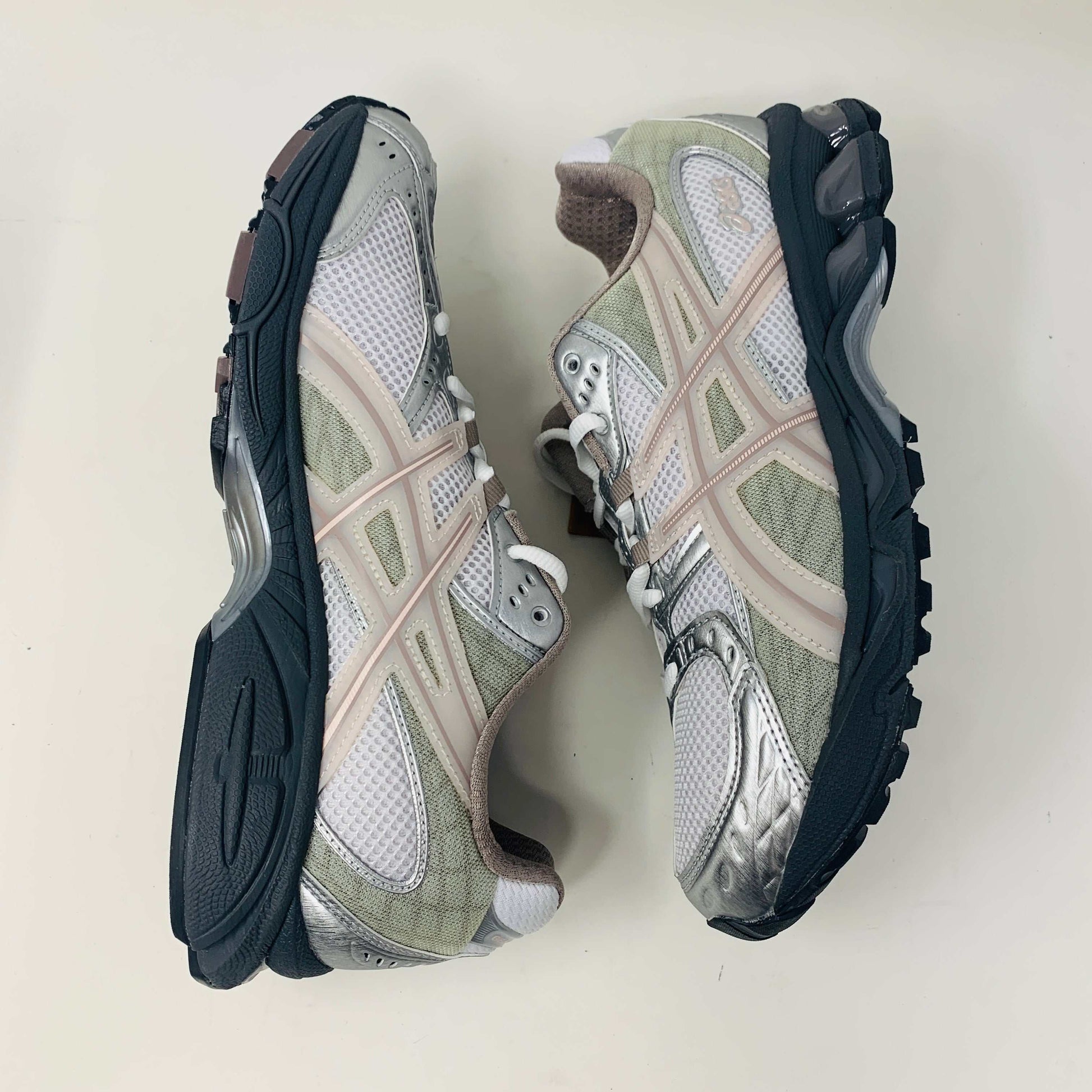The ASICS Gel-Nimbus 10.1 Kith White Morganite features white, gray, and light pink tones displayed on a shoebox. Includes two sets of laces: one brand new in white with black specks and one plain beige, sealed in plastic bags, ready for 2024.