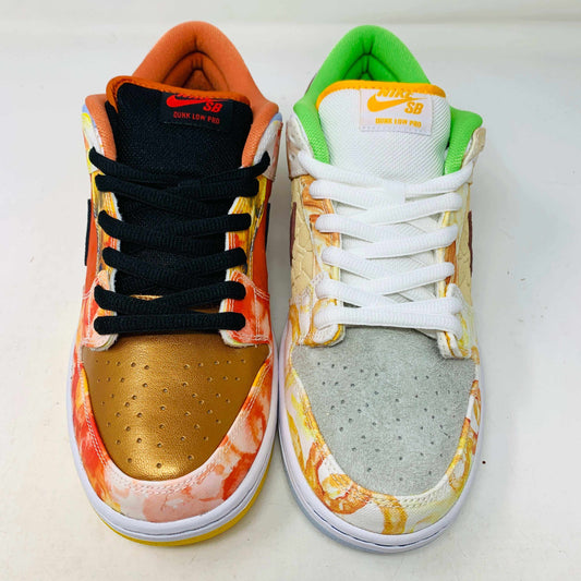 The Nike SB Dunk Low Street Hawker is a colorful sneaker displayed on a green and yellow box, featuring an authentic artistic design with brown, green, and orange tones. It has a quilted texture, white swoosh, white sole with light gray bottom, and comes with extra laces.