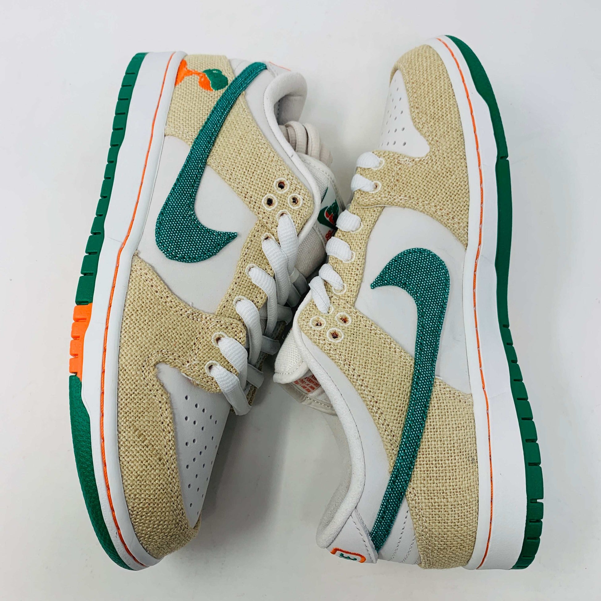 Front view of a brand new pair of Nike SB Dunk Low Jarritos sneakers in beige and white with green accents, featuring textured beige material, perforated toe panels, white laces, and swoosh logos on the tongues. Extra 2 laces included; displayed on a plain white background.