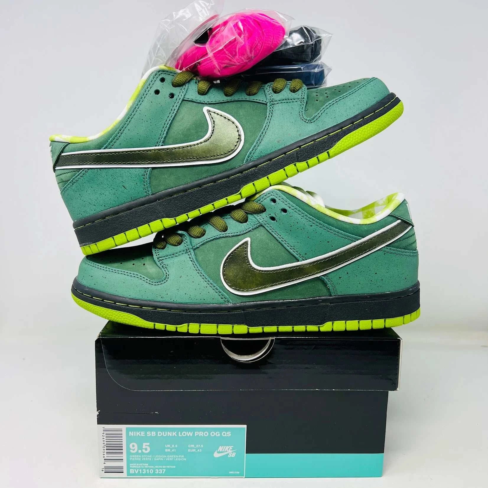The Nike SB Dunk Low Concepts Green Lobster sneakers, with silver Swooshes and displayed on their Shanghai Special Box, come with extra pink and black laces. They feature green midsoles and a checkered inner lining for that iconic touch.