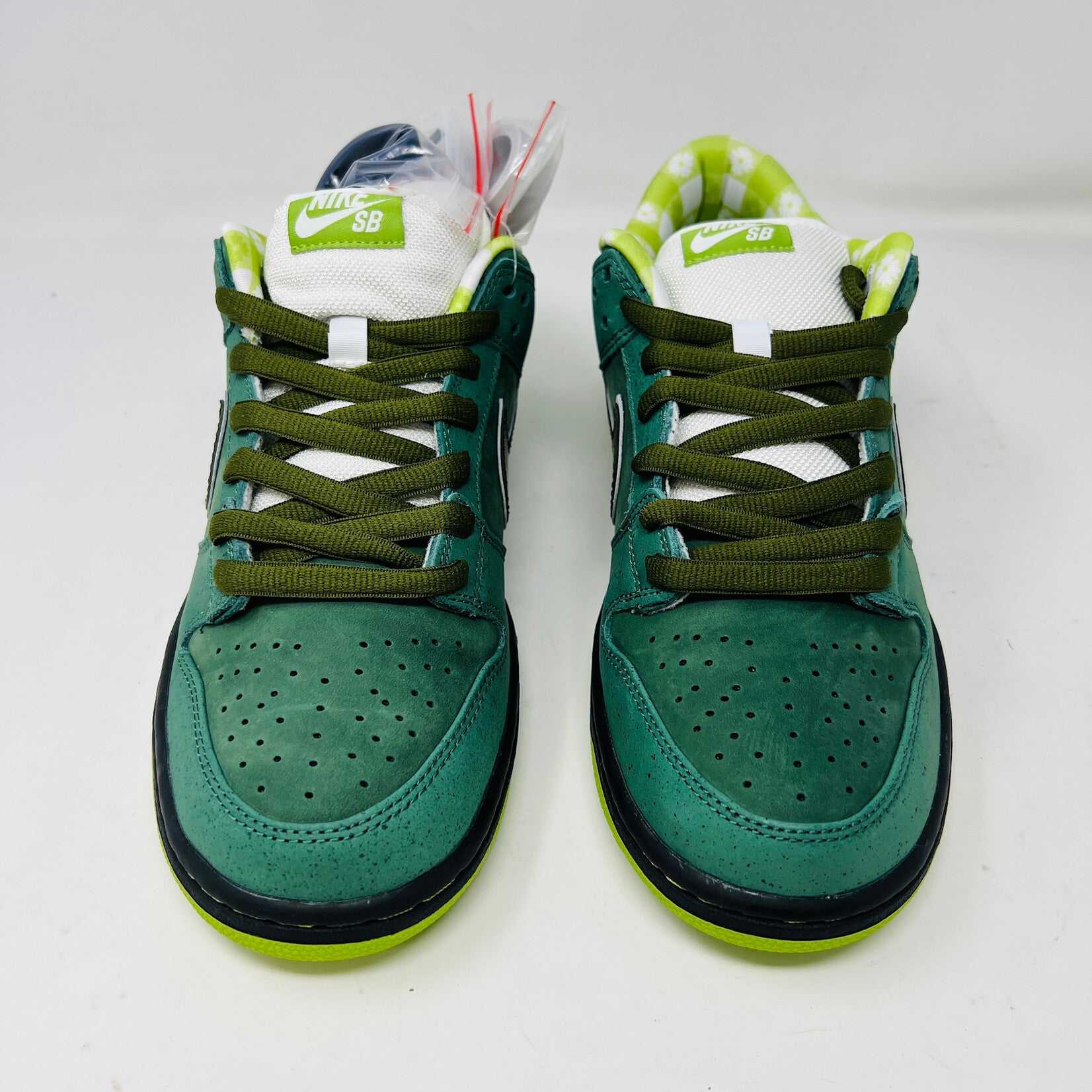 The Nike SB Dunk Low Concepts Green Lobster sneakers, with silver Swooshes and displayed on their Shanghai Special Box, come with extra pink and black laces. They feature green midsoles and a checkered inner lining for that iconic touch.