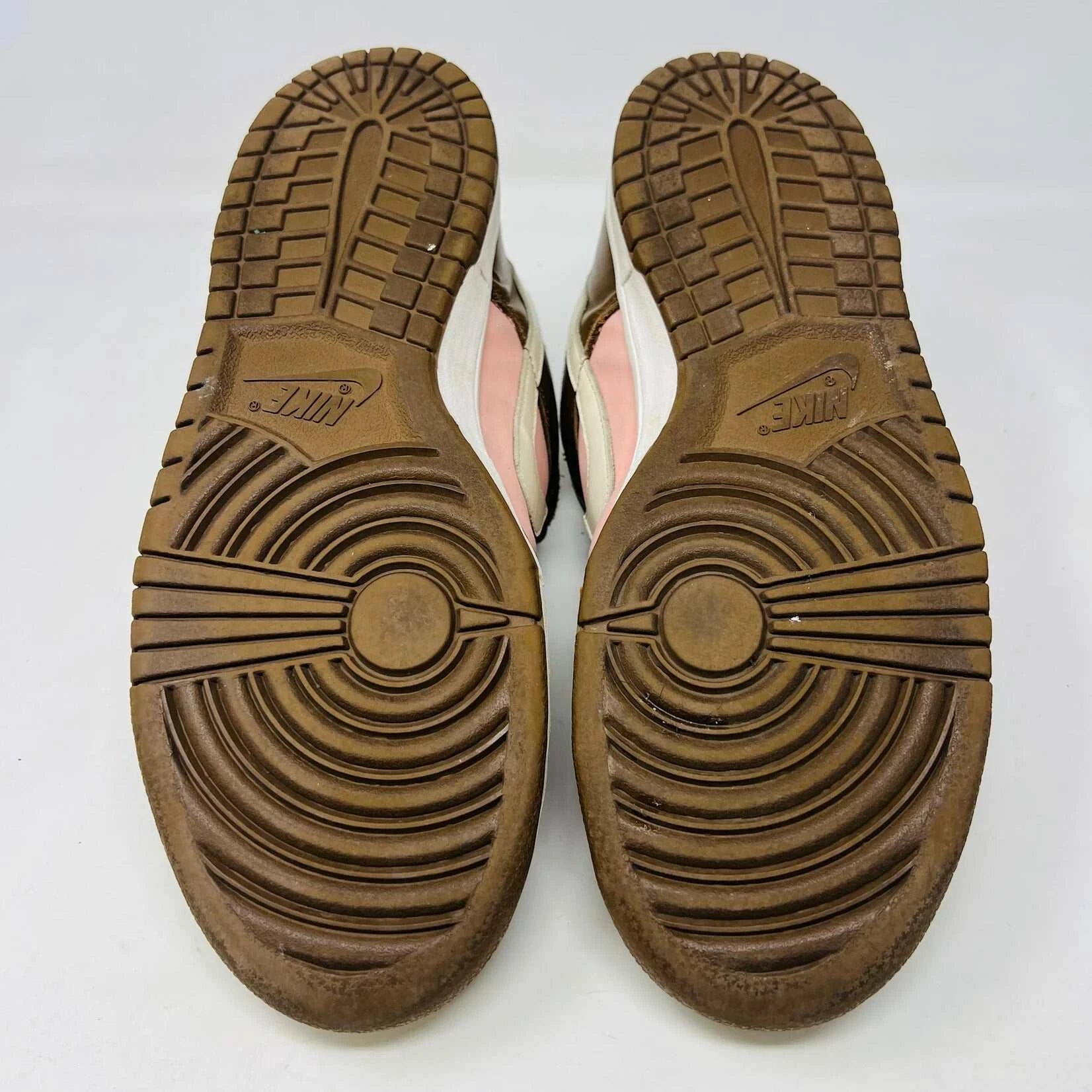 The Nike SB Dunk Low Stussy Cherry sneakers, in brown and pink with white midsoles, feature brown laces and a brand tag on the tongue, set against a plain white background.