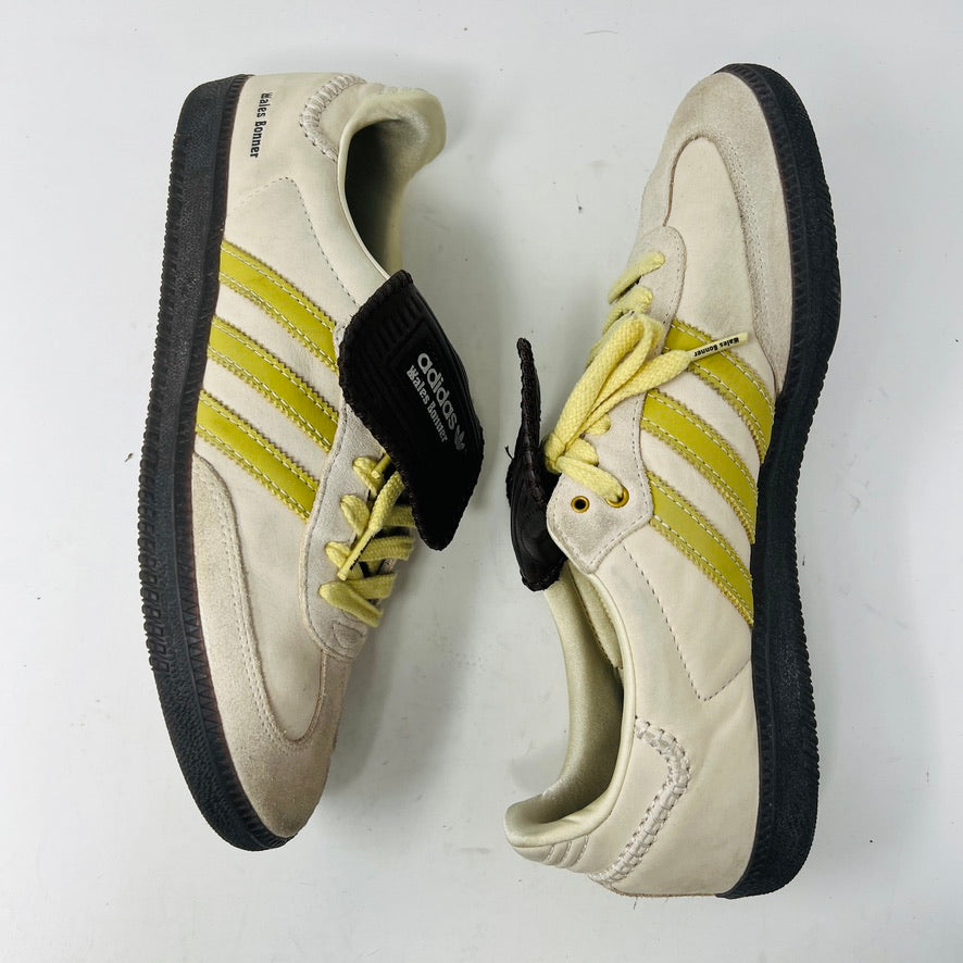 The 2023 adidas Samba Wales Bonner Ecrtin Brown sneakers feature beige uppers with three yellow stripes, a brown logo flap, and black soles. Despite general wear, the side and tongue branding stays distinct. Theyre displayed side by side on a white background.