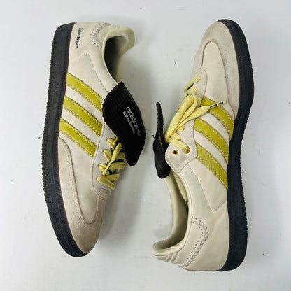The 2023 adidas Samba Wales Bonner Ecrtin Brown sneakers feature beige uppers with three yellow stripes, a brown logo flap, and black soles. Despite general wear, the side and tongue branding stays distinct. Theyre displayed side by side on a white background.