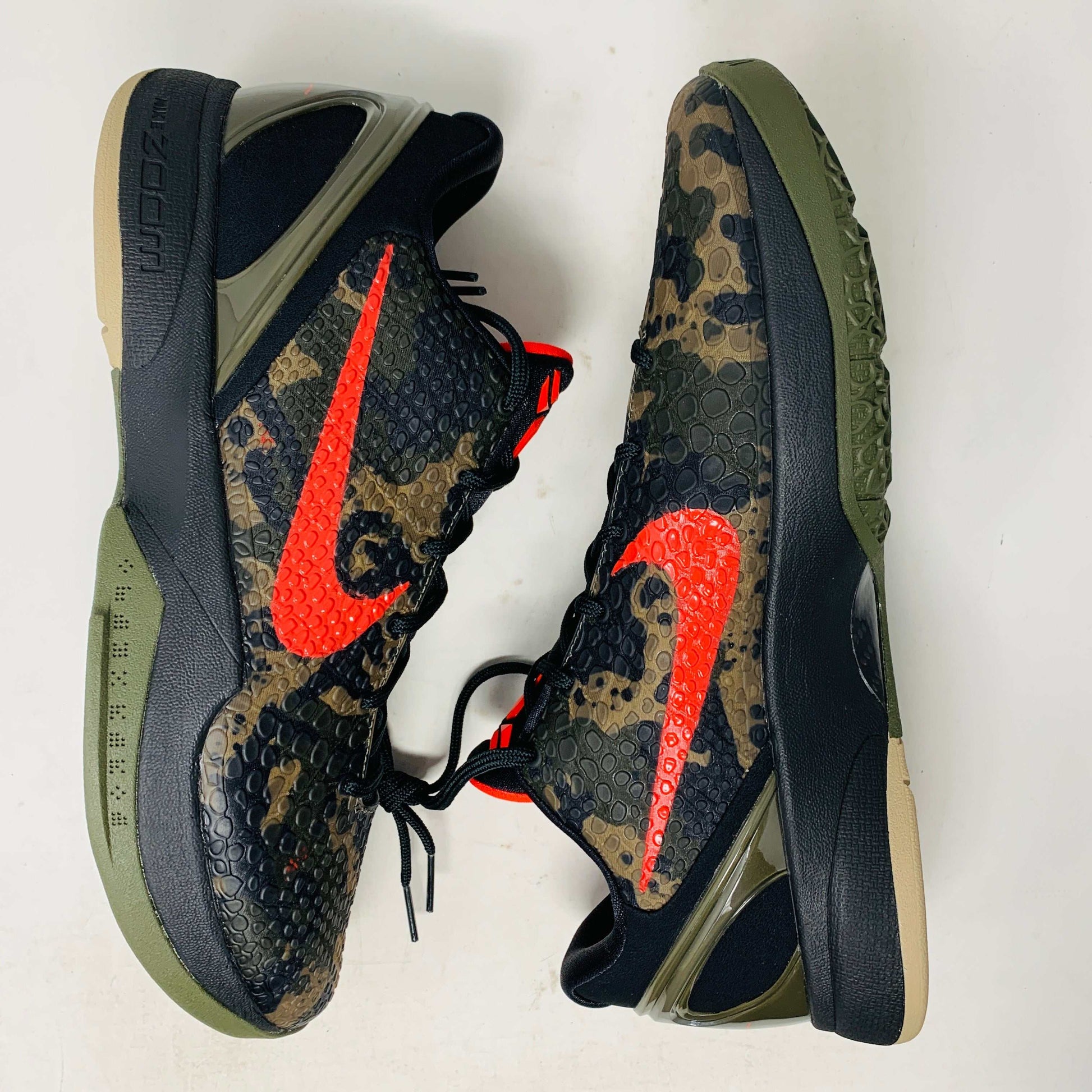 The 2024 Nike Kobe 6 Protro Italian Camo features a textured gray upper with a bright red swoosh, sits on a black shoe box, and has a greenish midsole labeled Zoom. The sleek black lace system completes this authentic sporty sneaker.