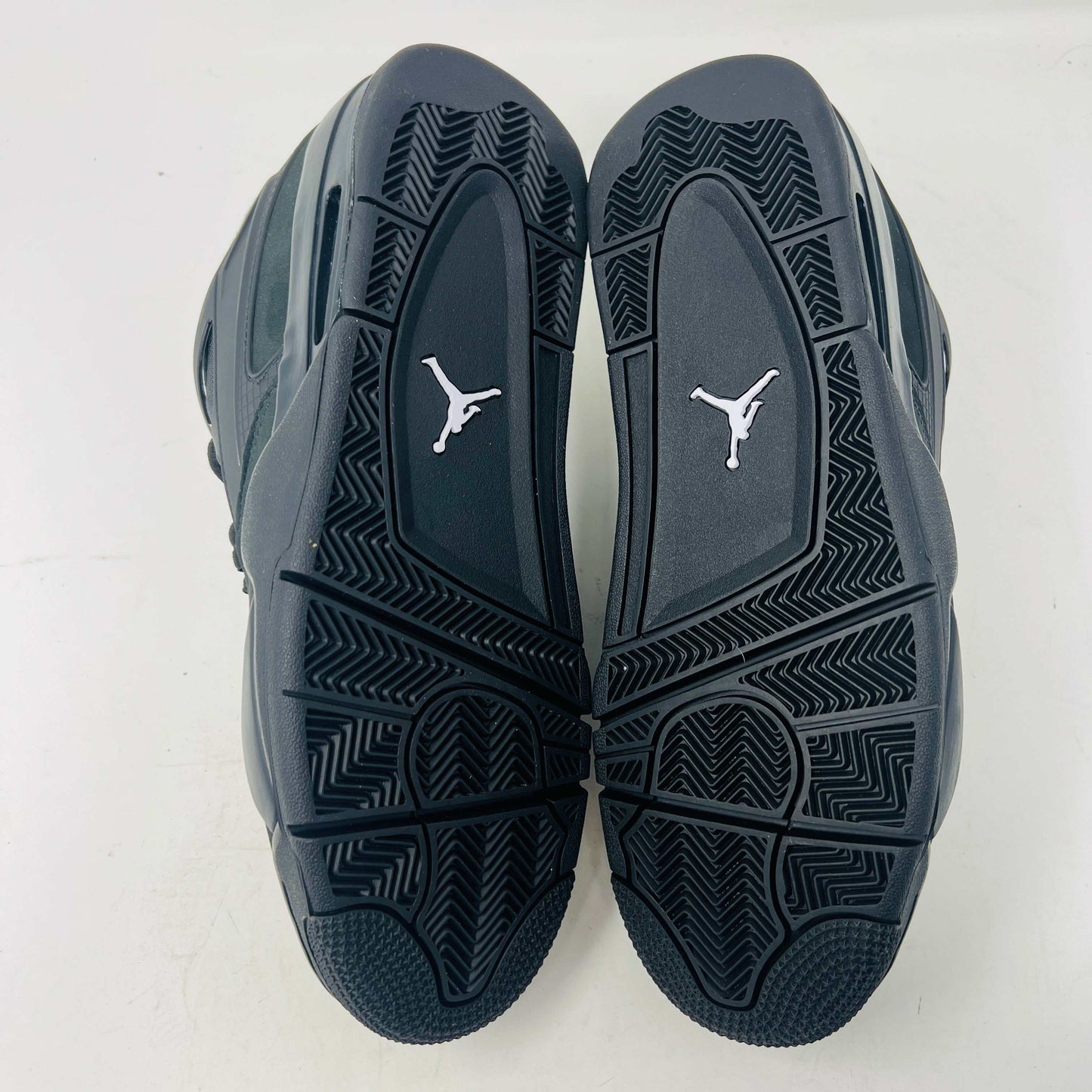 Jordan 4 RM Black Cat sneakers with sleek black design and grey accents, showcasing the outsole and premium leather.