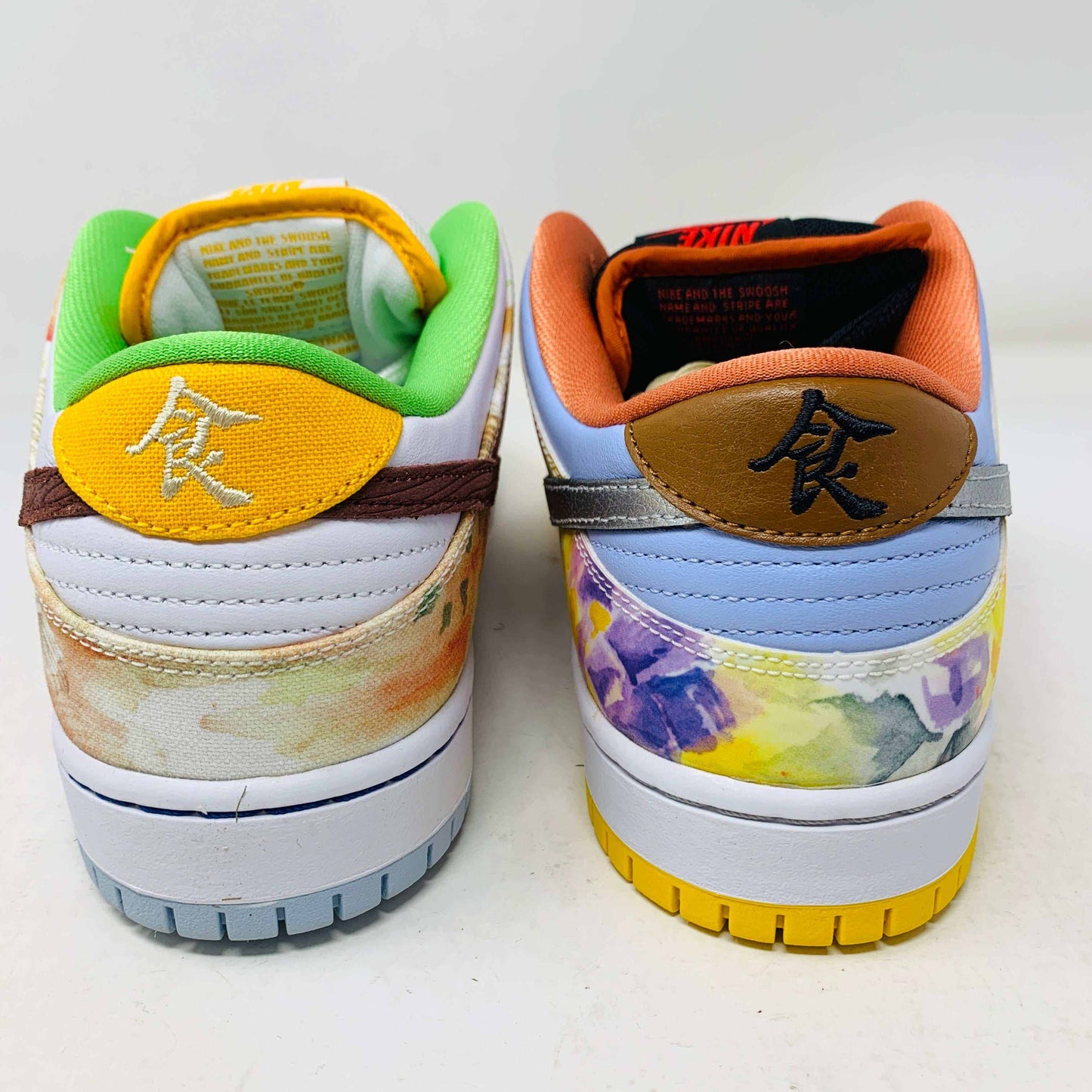 The Nike SB Dunk Low Street Hawker is a colorful sneaker displayed on a green and yellow box, featuring an authentic artistic design with brown, green, and orange tones. It has a quilted texture, white swoosh, white sole with light gray bottom, and comes with extra laces.
