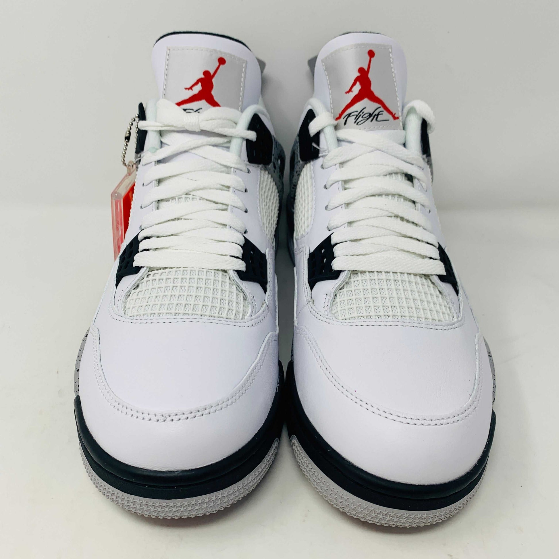 Check out the Jordan 4 White Cement 2016, a white sneaker with black and gray speckles. It features a small red jumping logo, comes in a matching box, and includes the classic 2016 Jordan hang tag for authenticity.