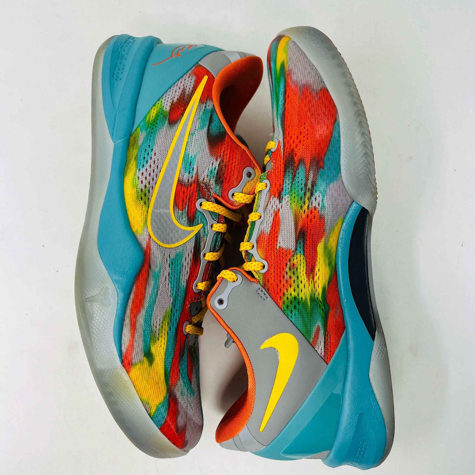 The Nike Kobe 8 Protro Venice Beach (2024) sneakers, featuring vibrant red, blue, yellow, and green brushstroke patterns with clean uppers and yellow laces paired with an orange lining, boast excellent condition at 8.5/10. A distinct logo adorns the gray tongue as they lay side by side on a white background.