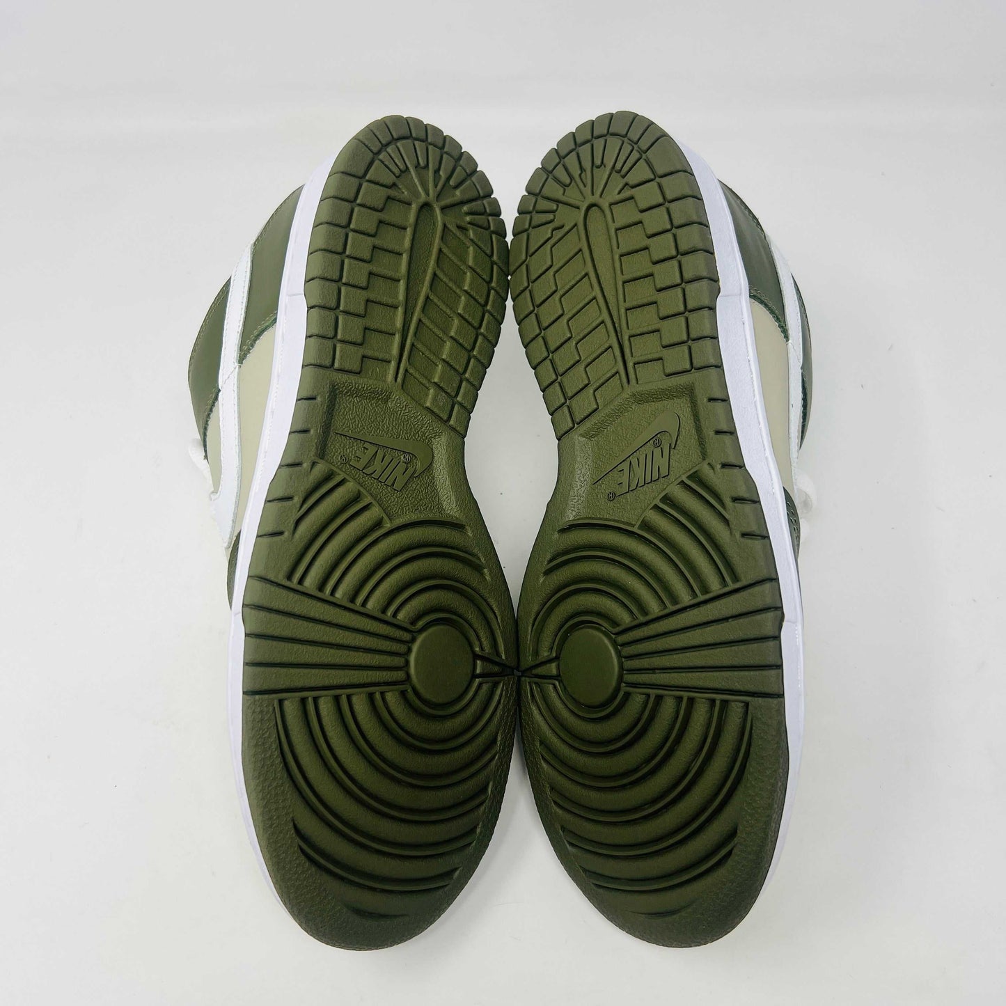 A Nike Dunk Low Light Stone shoe in green and beige with brand new white laces is displayed atop an orange Nike box. Extra white laces are in front, ensuring this 100% authentic pair from the Nike Dunk collection is ready to step out in style.