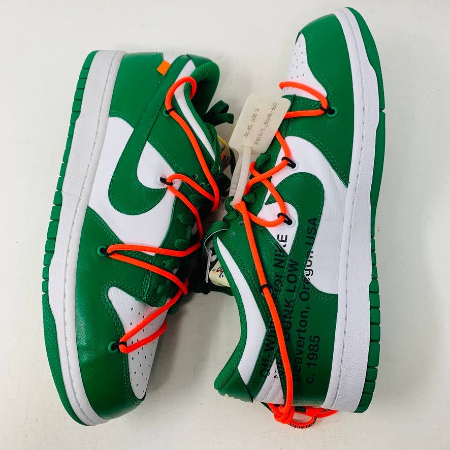 The Nike Dunk Low Off White Pine Green sneaker, accented with bright orange laces, rests on a shiny silver box. This authentic 2019 release by Nike boasts a sleek white tag, highlighting its new allure.
