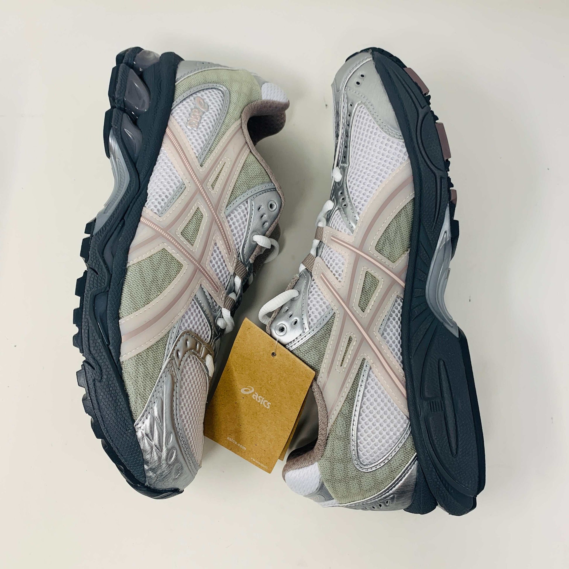 The ASICS Gel-Nimbus 10.1 Kith White Morganite features white, gray, and light pink tones displayed on a shoebox. Includes two sets of laces: one brand new in white with black specks and one plain beige, sealed in plastic bags, ready for 2024.