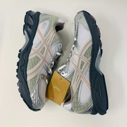 The ASICS Gel-Nimbus 10.1 Kith White Morganite features white, gray, and light pink tones displayed on a shoebox. Includes two sets of laces: one brand new in white with black specks and one plain beige, sealed in plastic bags, ready for 2024.