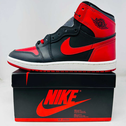 Jordan 1 Retro High '85 OG Bred (2025) sneaker with red and black colorway, includes red laces and hang tag, brand new condition on Nike box.